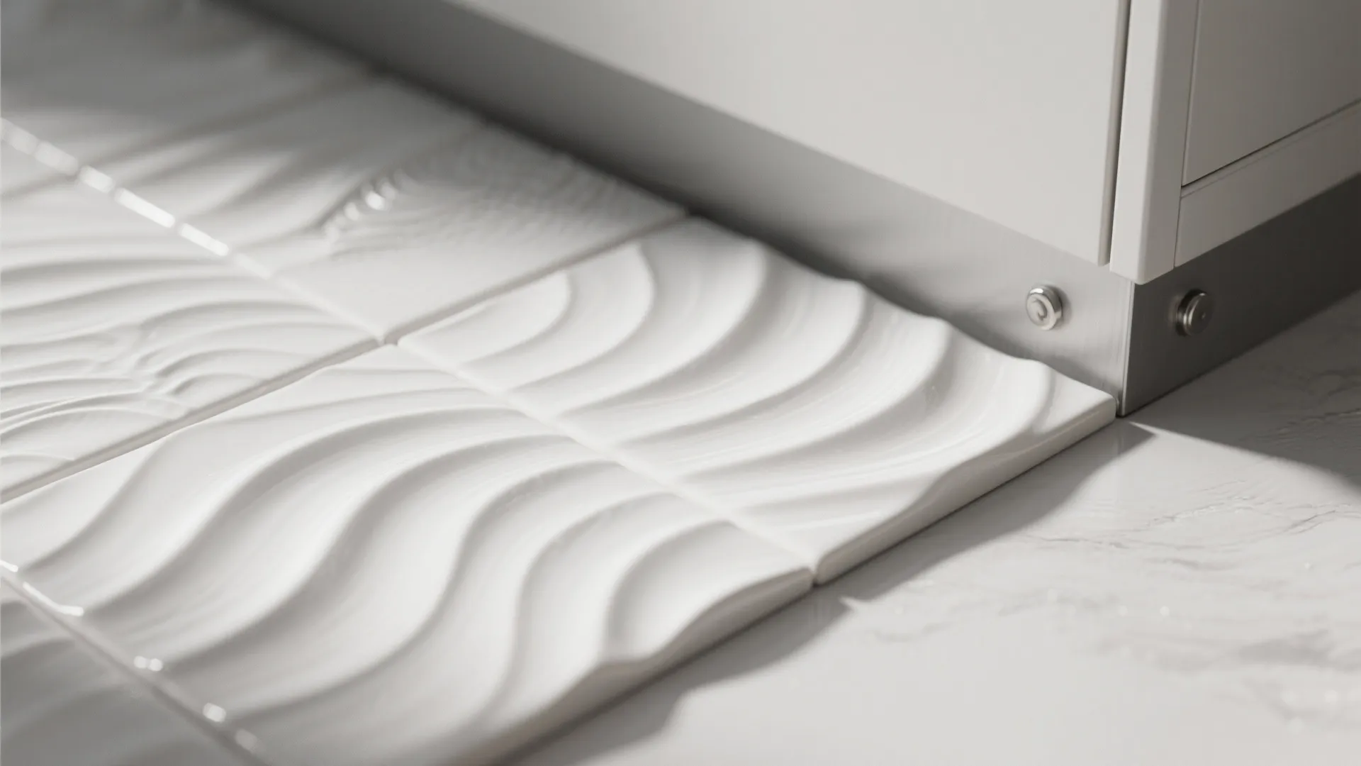 Close up of white wall tiles with wavy pattern placed beside a white kitchen cabinet