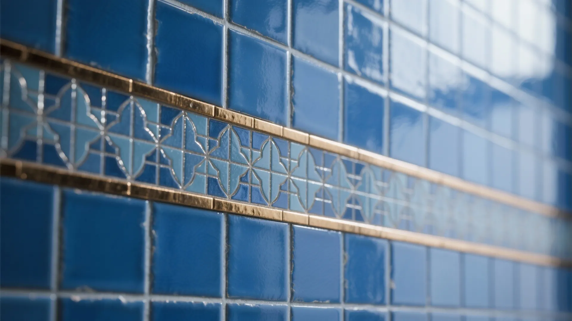 Detail of blue subway tile with narrow patterned mosaic accent band and brass trim