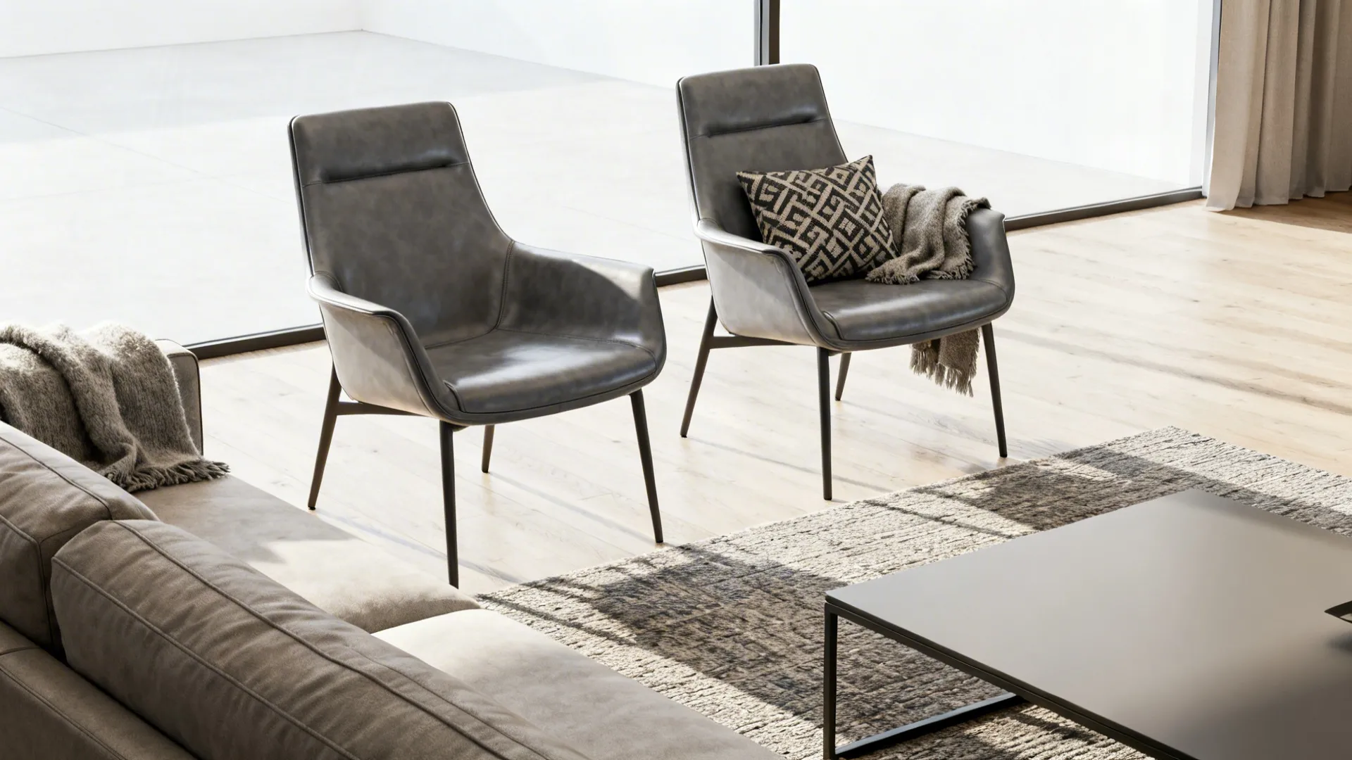 Two slim gray leather accent chairs paired opposite a sofa with a wool throw and patterned cushion.