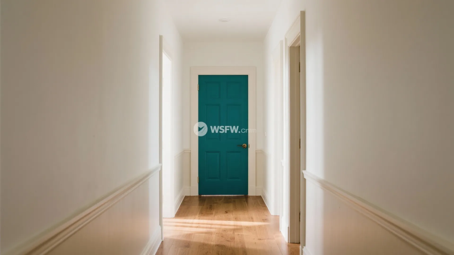 Bright white hallway with light wood flooring leading to a bold dark blue room door