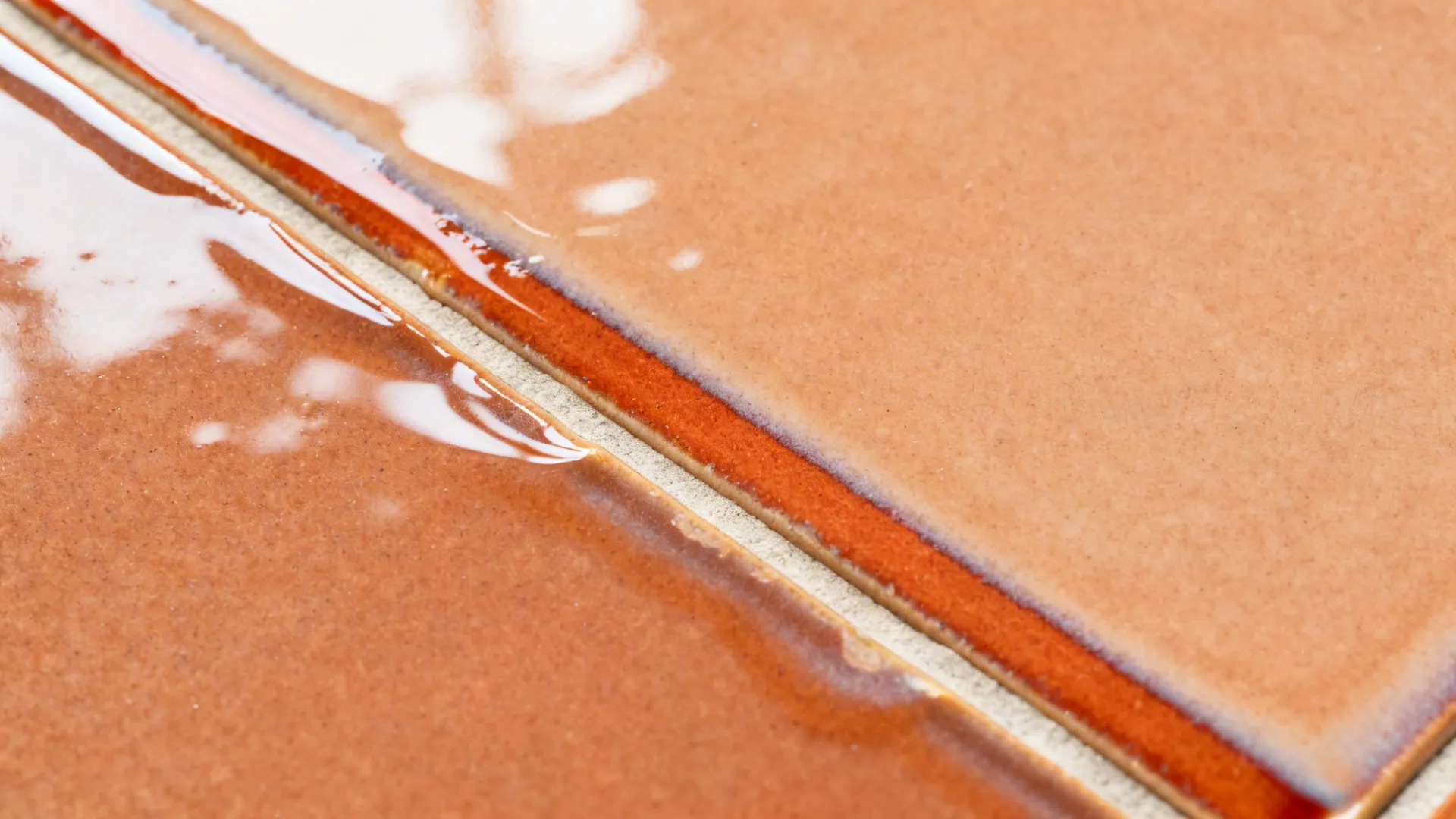 Macro of accent stripe blending glossy glass tiles with glazed terracotta and neat grout lines.