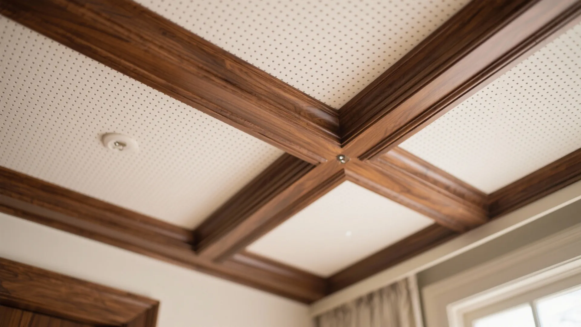 Close up view of dark wood ceiling beams on a white dotted surface with wall light