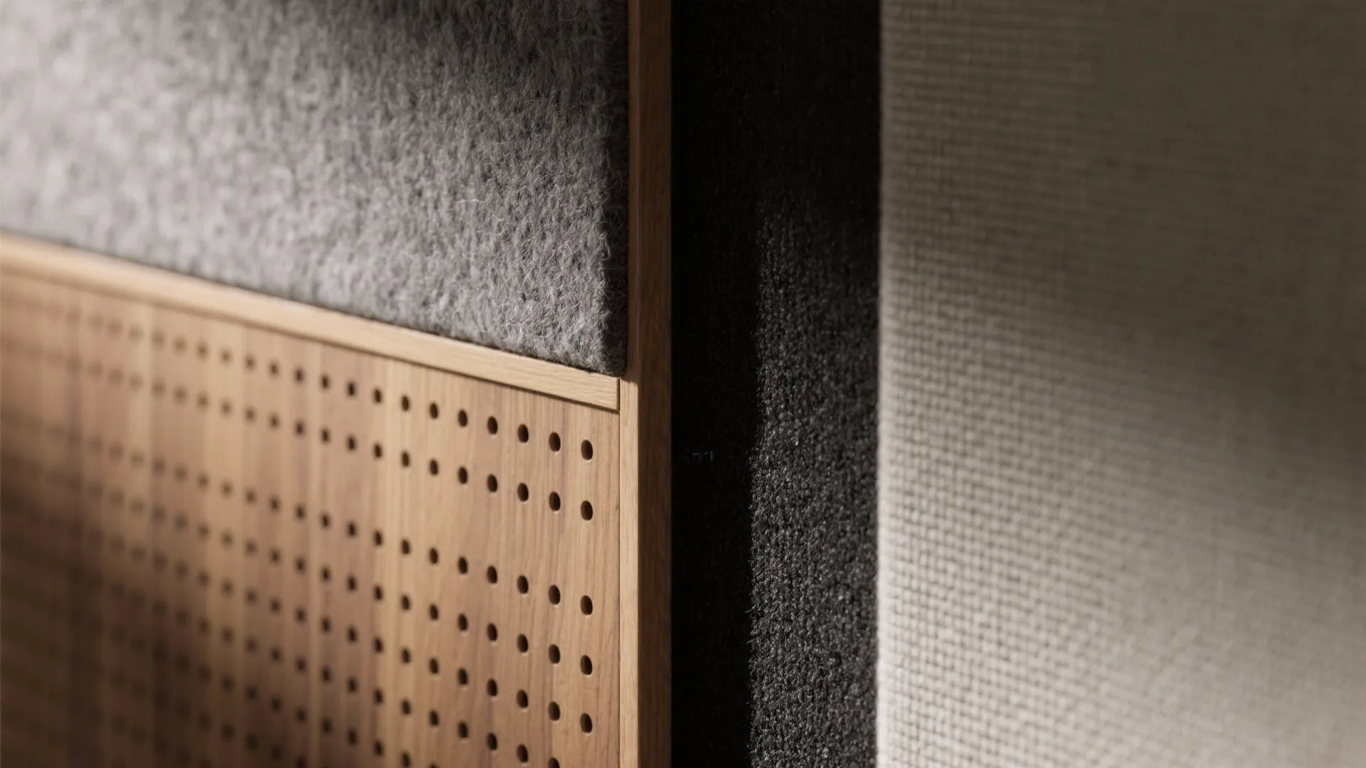 Close up view of a wood wall panel with small holes and grey fabric material