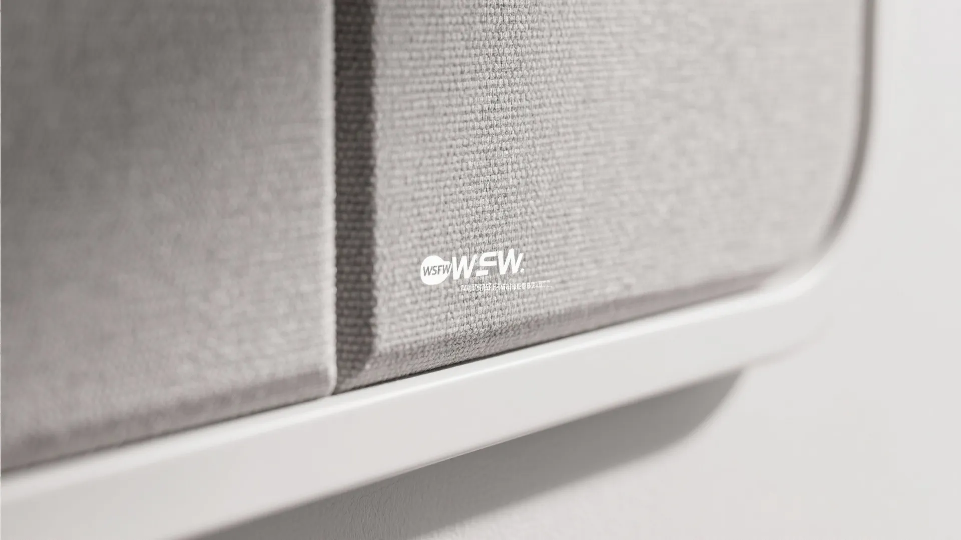 Close up view of grey fabric wall panel texture with white frame and small logo detail