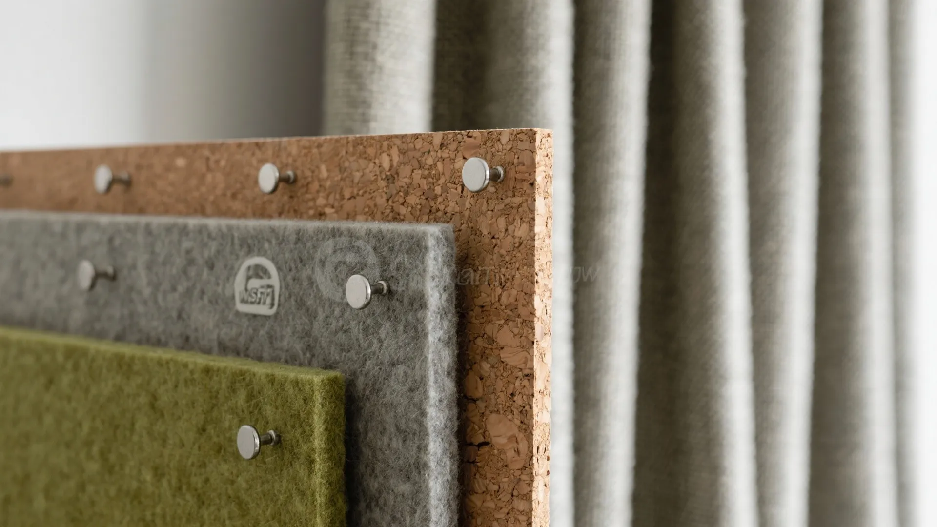 Textured cork board layered with grey and green felt panels held by small round metal pins