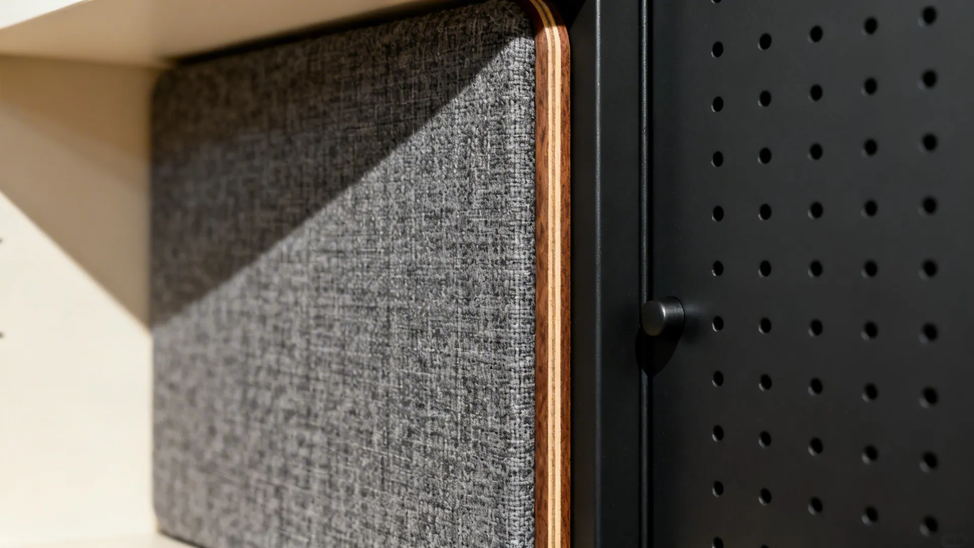 Macro of fabric-wrapped acoustic panel and walnut shelf edge detail.