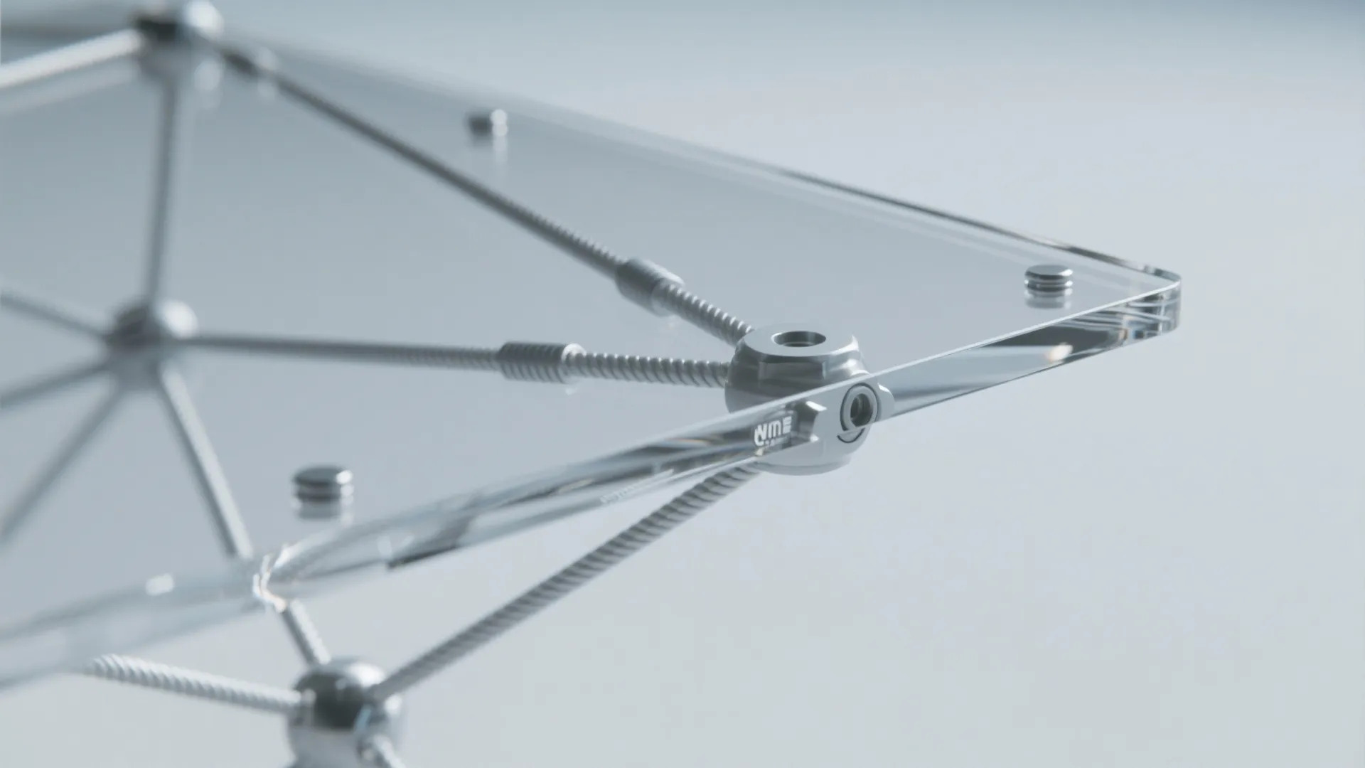 Close up of a clear glass table surface with silver metal joints and thin support rods
