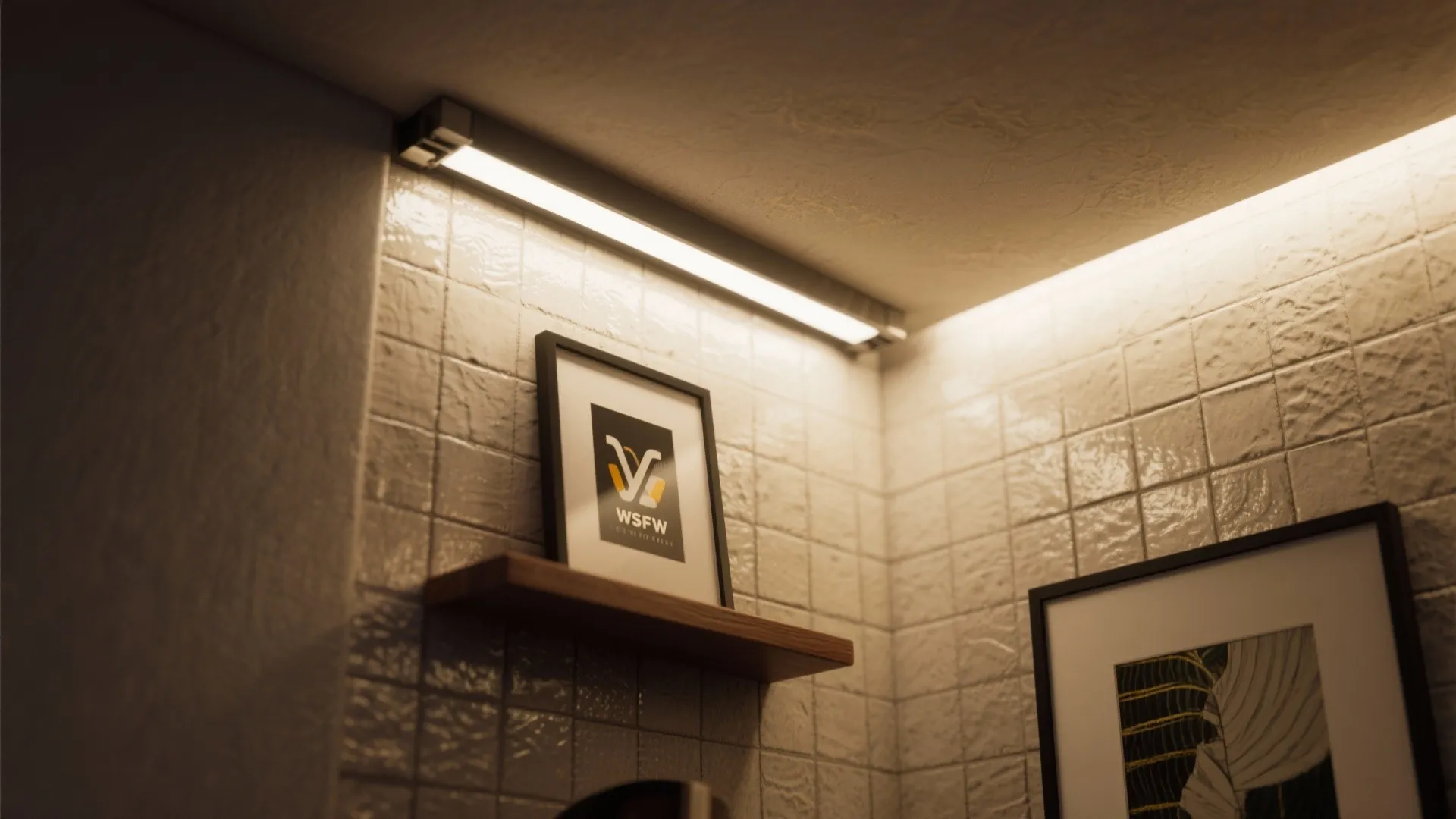 Close up of a long light fixture shining on a shelf with framed art and tiles