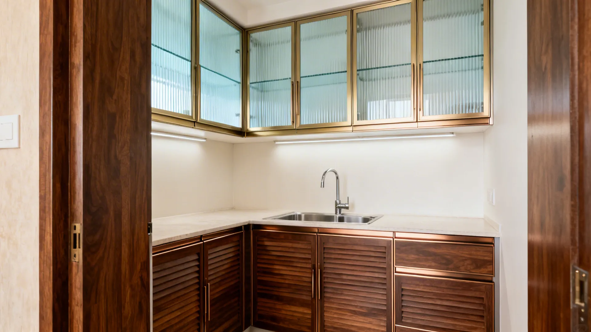 Modern kitchen corner with wooden cabinets and glass wall storage units featuring golden metal frames