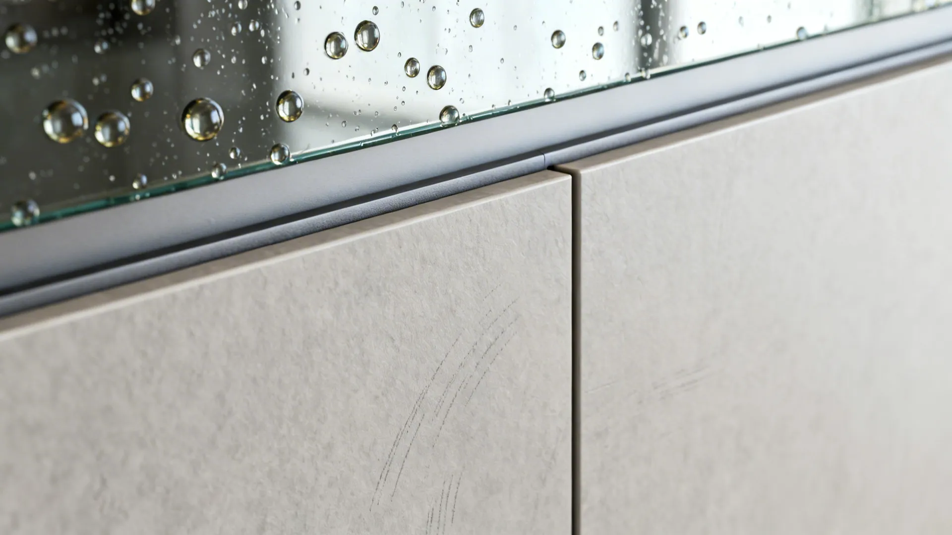 Macro of anti-fingerprint laminate and beading on glass backsplash showing easy-clean surfaces.