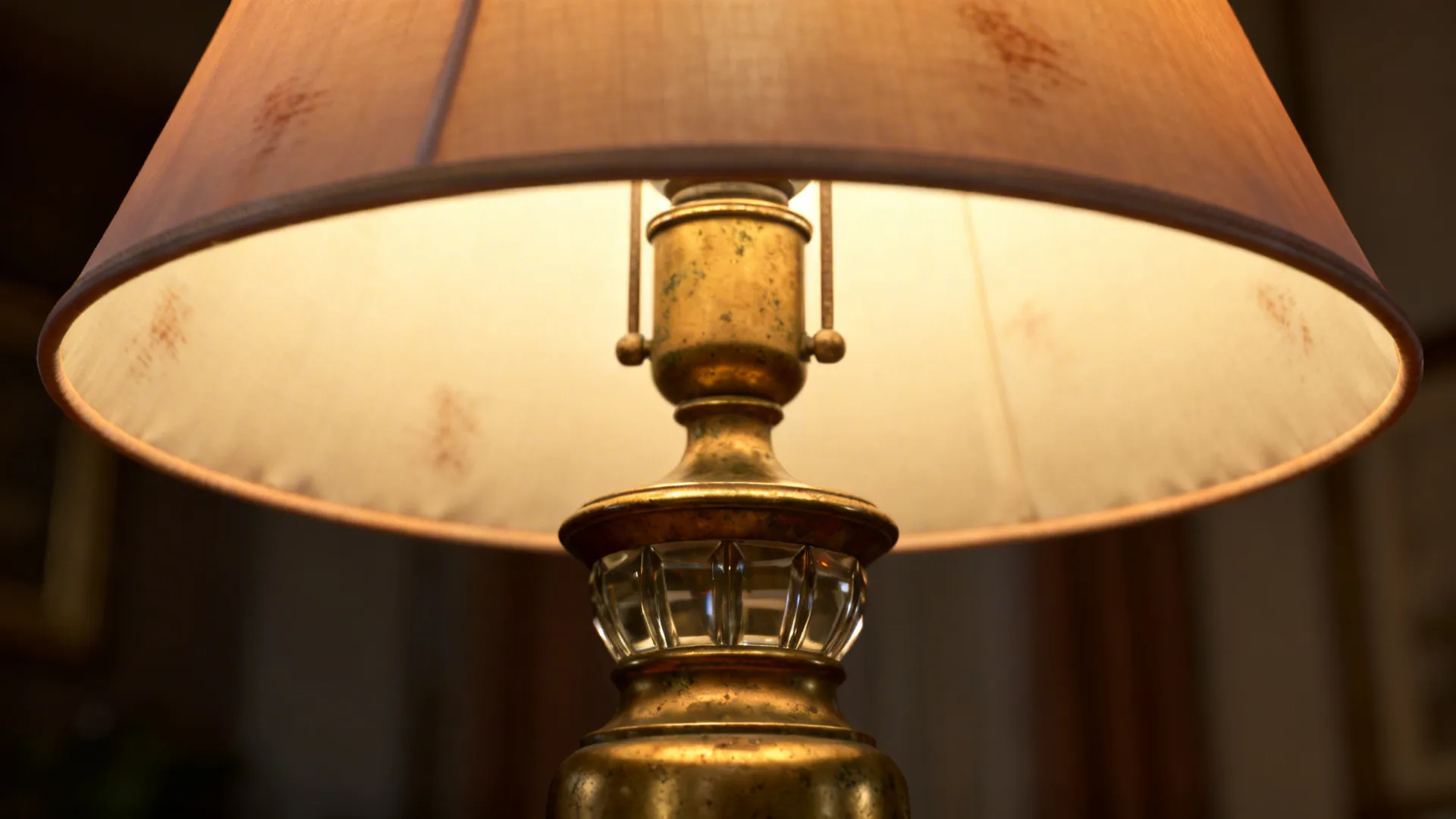 Macro of an antique brass lamp base with silk shade showing warm glow and metal texture