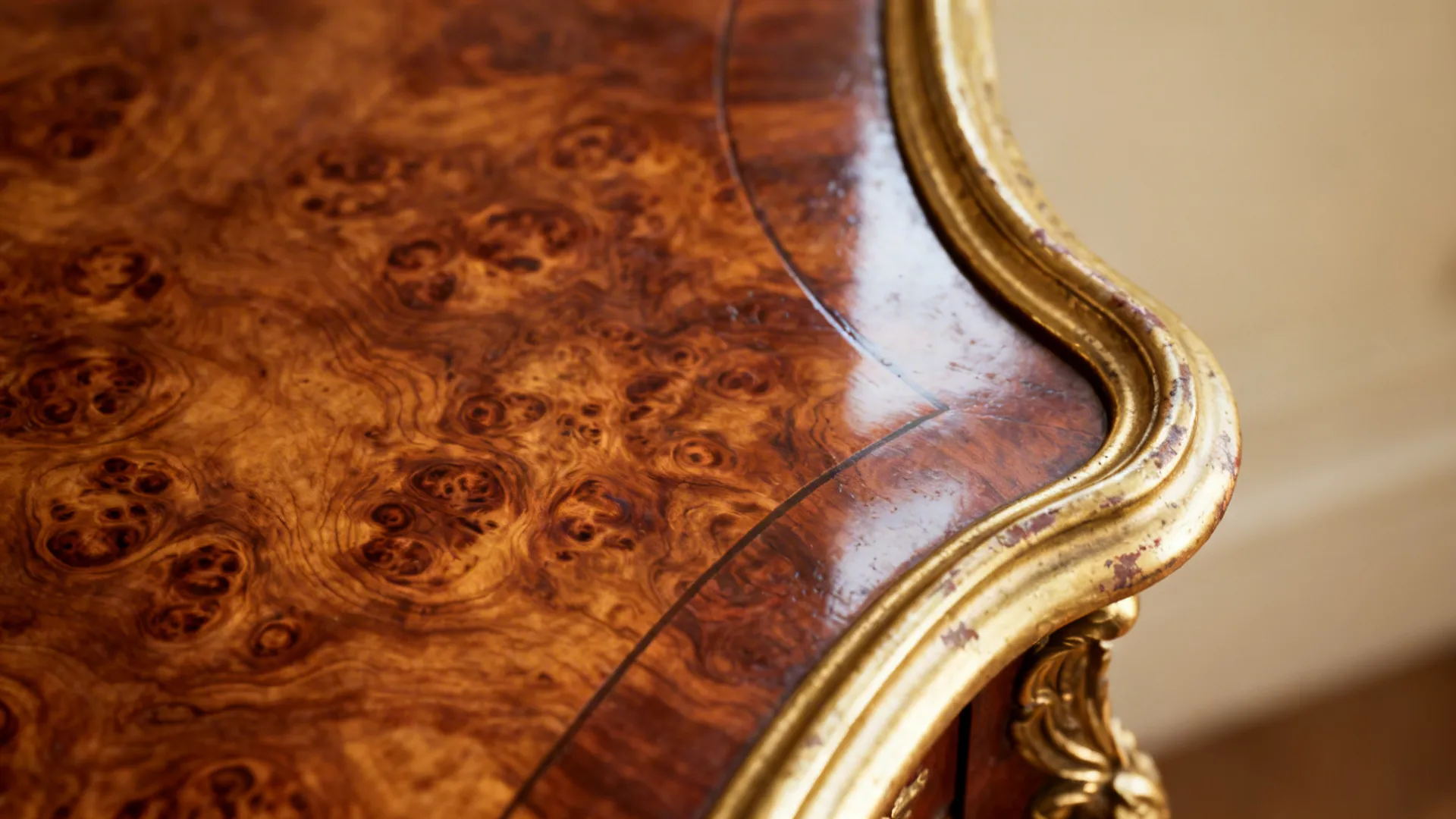 Macro of a burl wood table and worn gilt frame showing rich grain and patina.