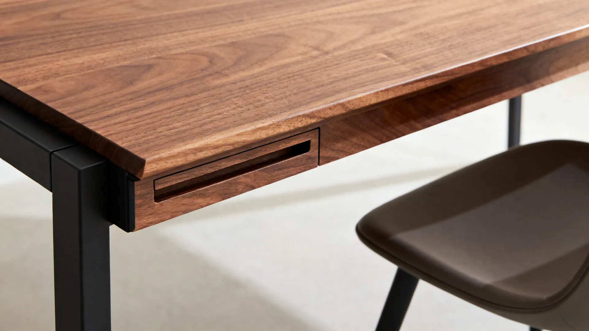 Close up of wooden table top with a small built in drawer and black legs