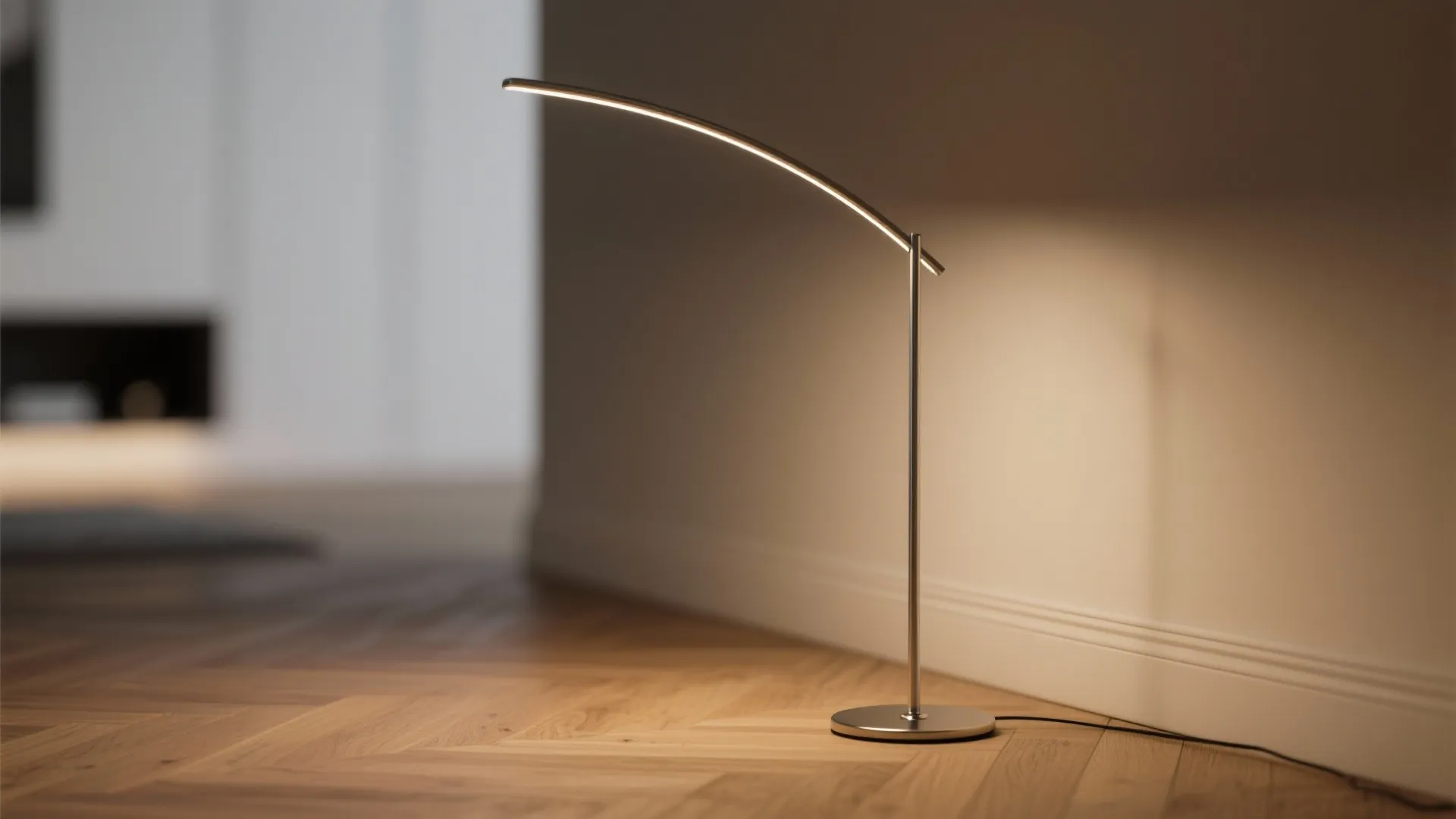Close-up of a slim arc lamp's low-profile base and slender stem in a modern living room.