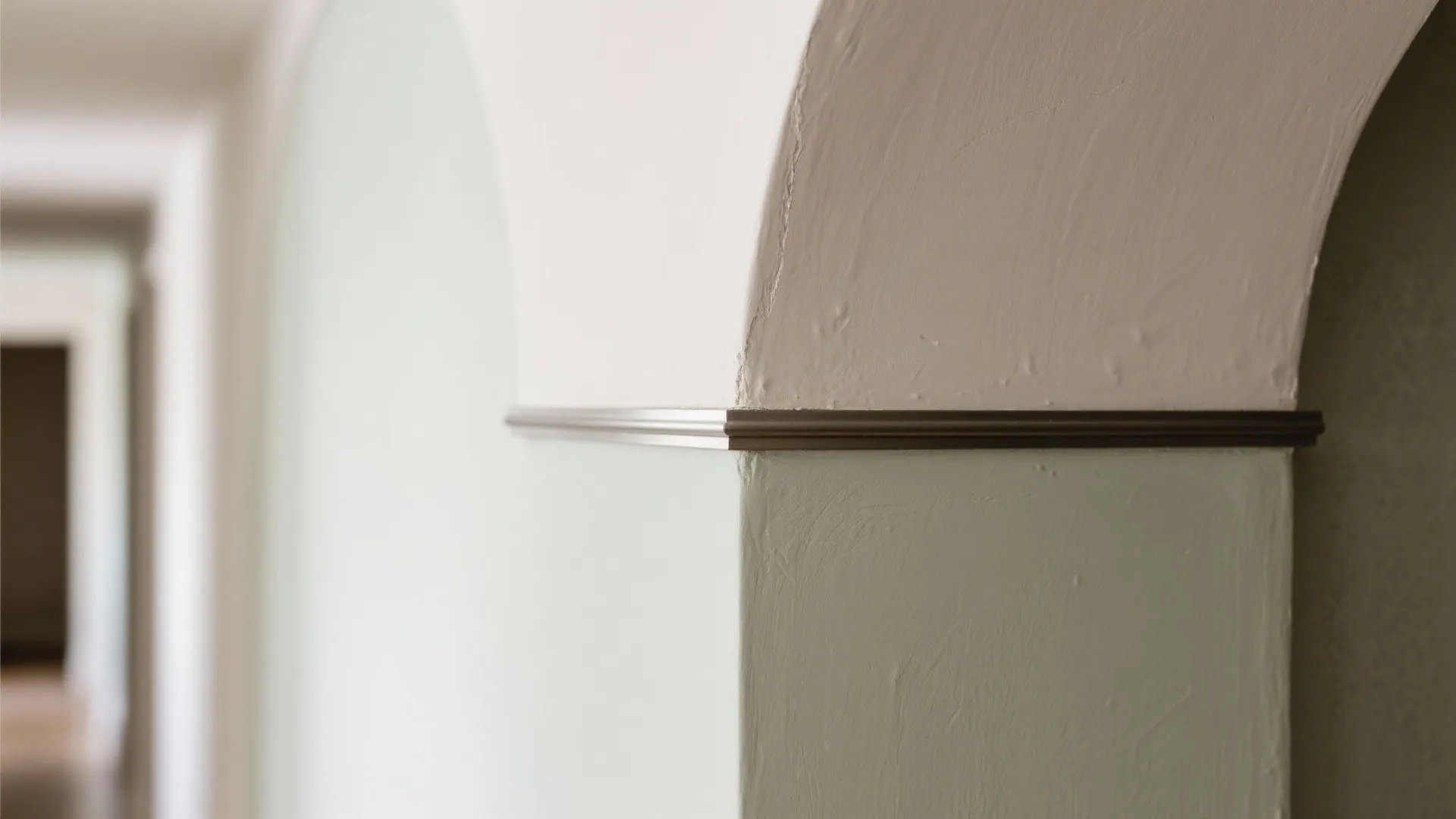 Close up view of wall corner with arched top and dark metal trim for protection