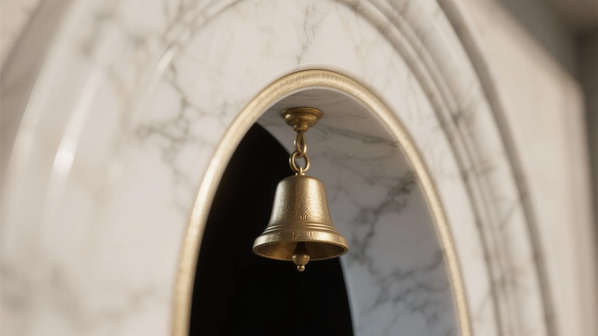 Close-up of a slender off-white marble arch edge with matte brass hanger in warm light.