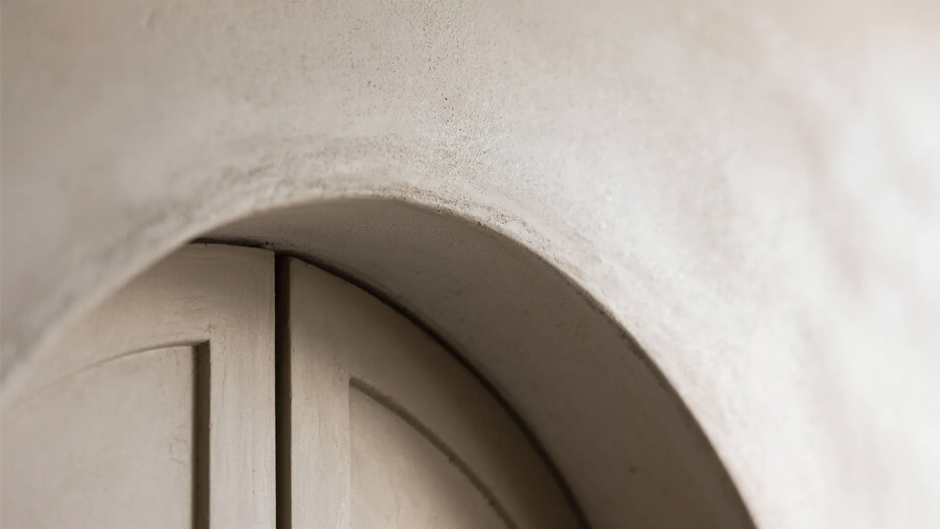 Close-up view of a curved arched doorway showing the smooth gray textured wall panel details