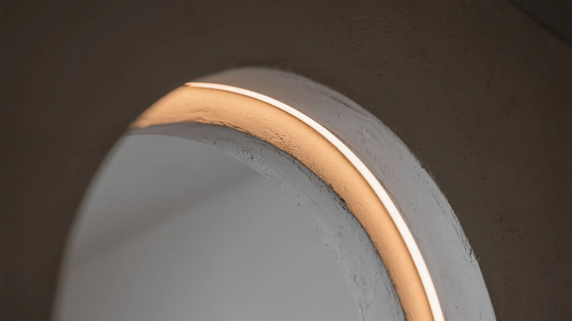 Detail of an arched wall opening with warm hidden light strip inside a modern home