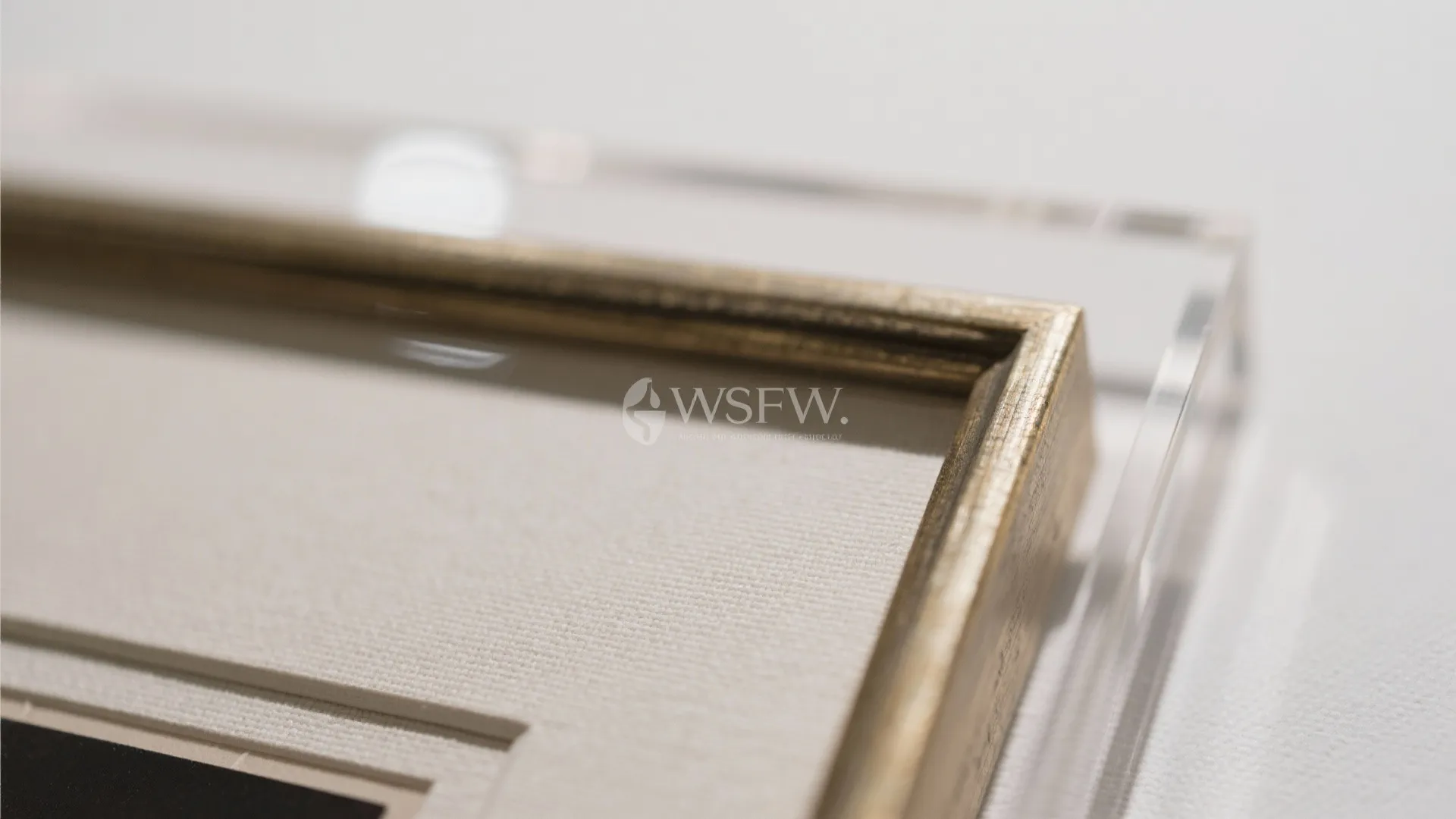 Macro of museum-grade frame with linen mat and UV acrylic glazing details.