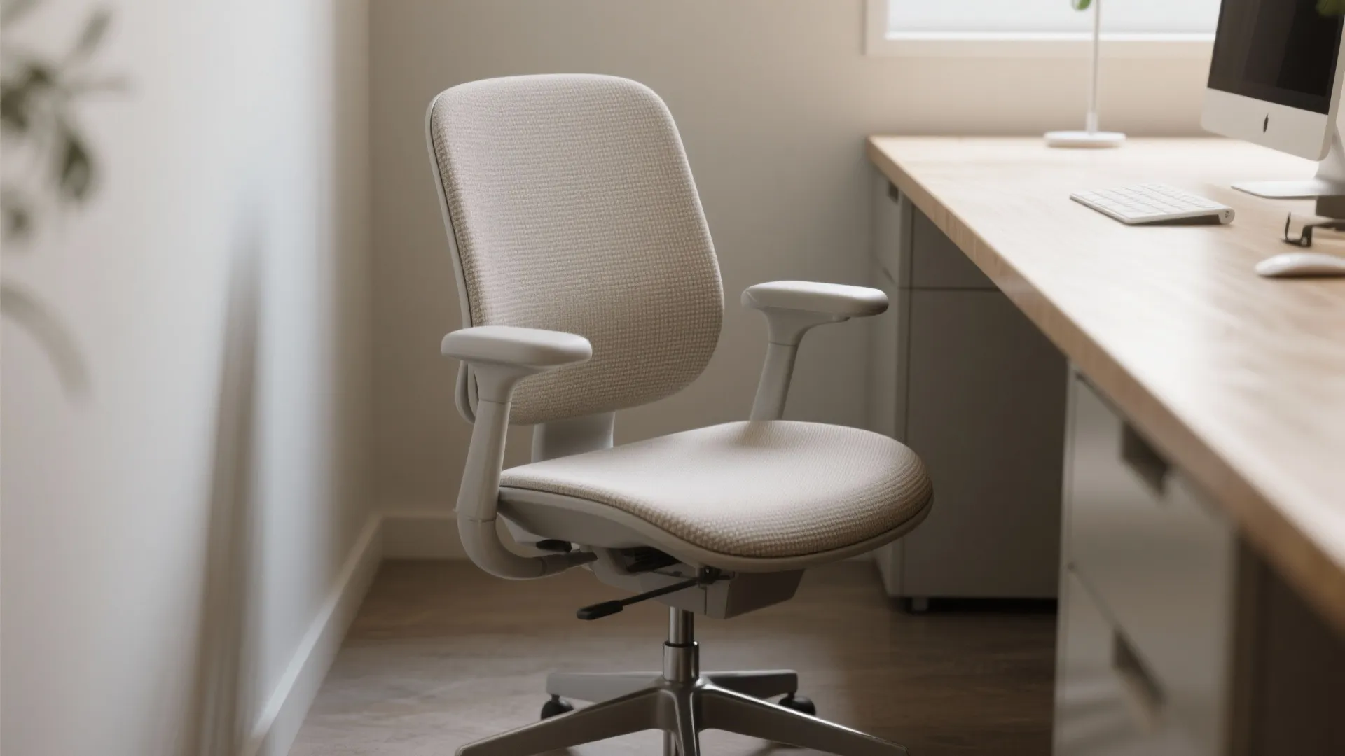 Armless ergonomic chair beside a narrow countertop desk, showing adjustable seat and lumbar support in a compact workspace.