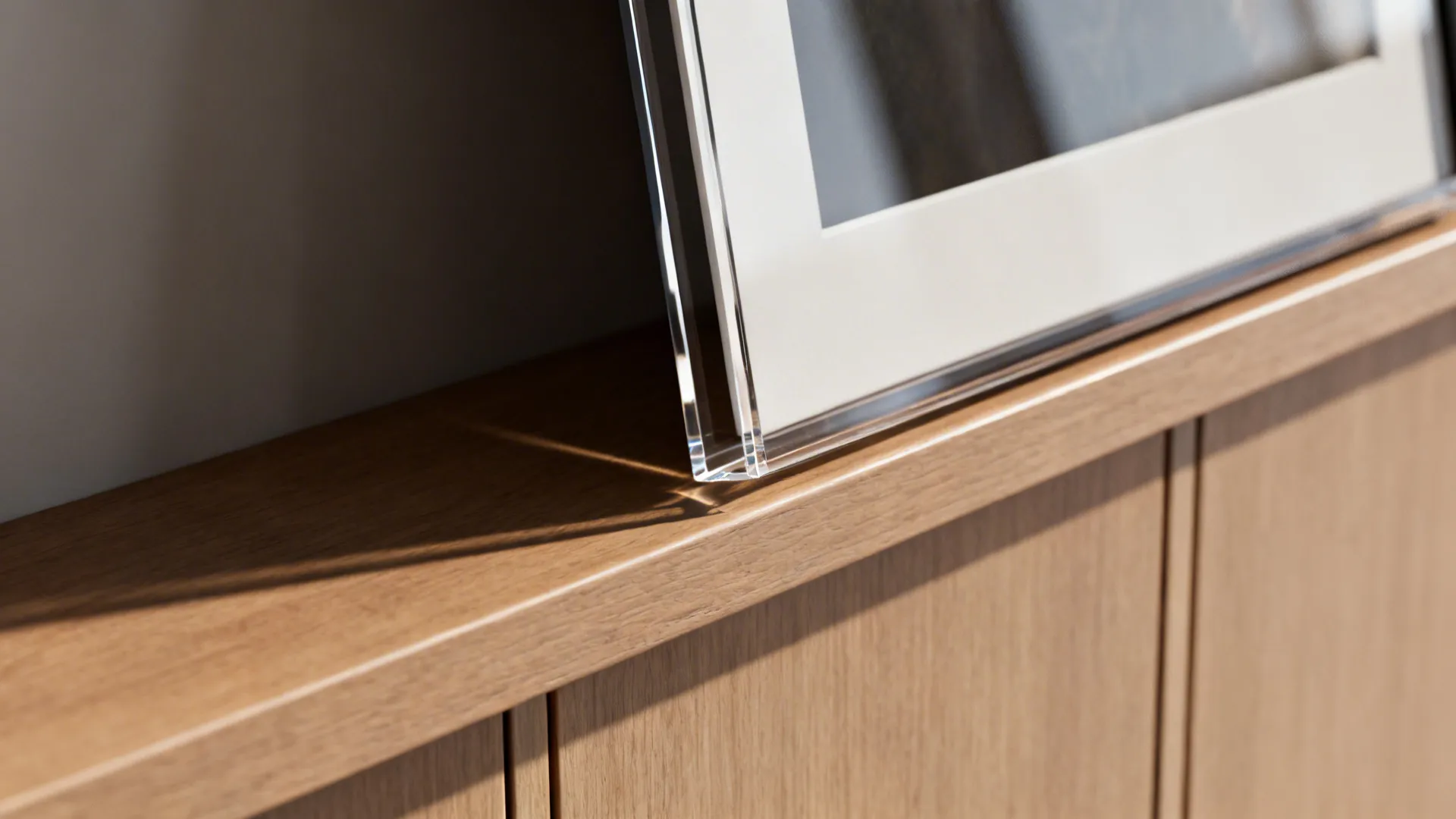 Close-up of an acrylic-glazed frame with clean matting on a slim wood ledge.