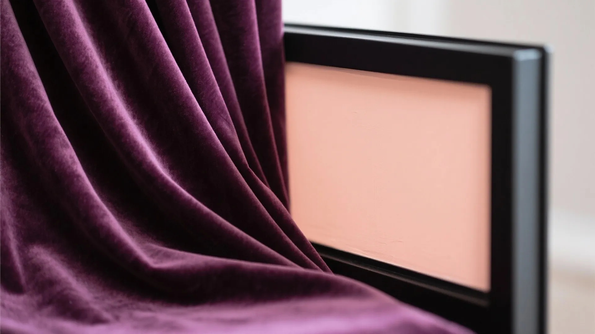 Close up view of purple velvet fabric texture next to a pink framed wall art
