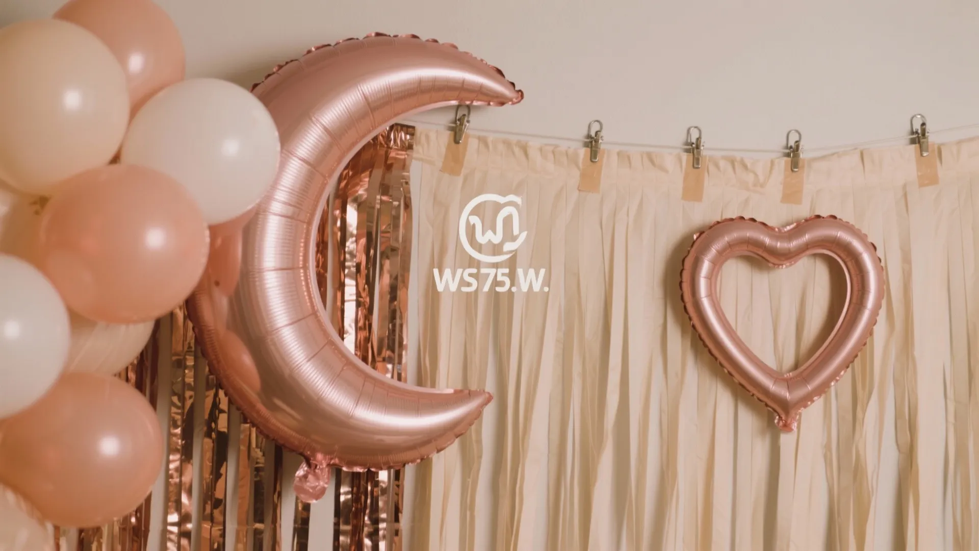 Rose gold moon and heart balloons hanging against a cream fringe backdrop for party decoration