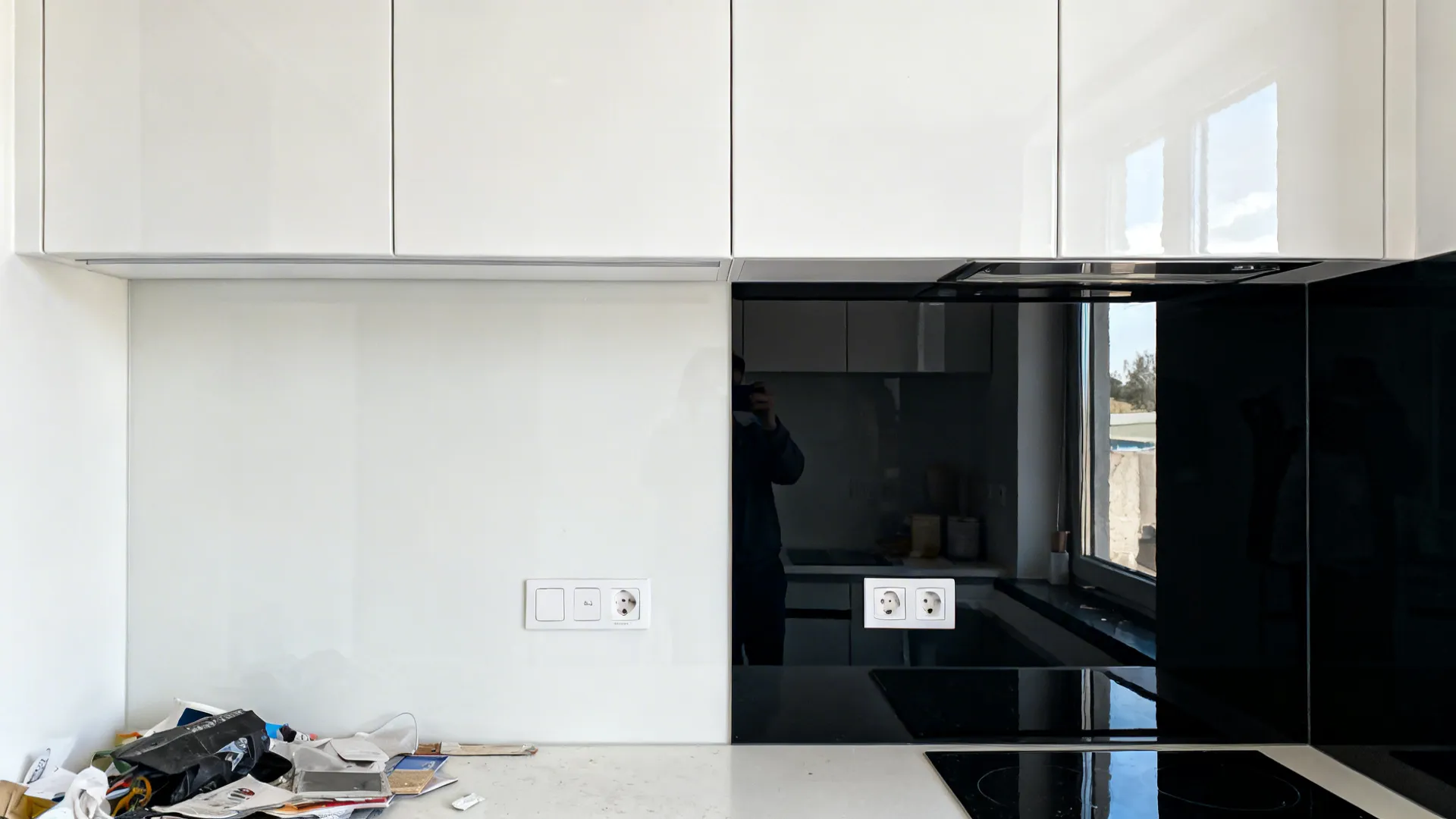 Split view comparing a plain white backsplash to a sleek black tempered-glass upgrade.