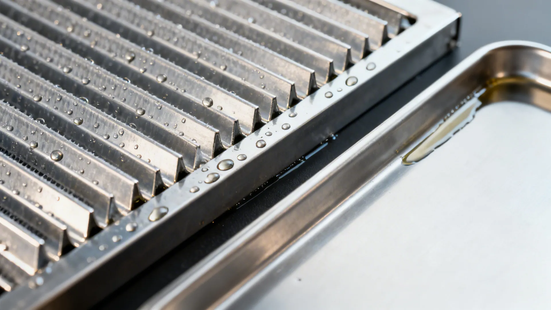 Macro view of stainless baffle filter fins with tiny oil beads and tray detail.