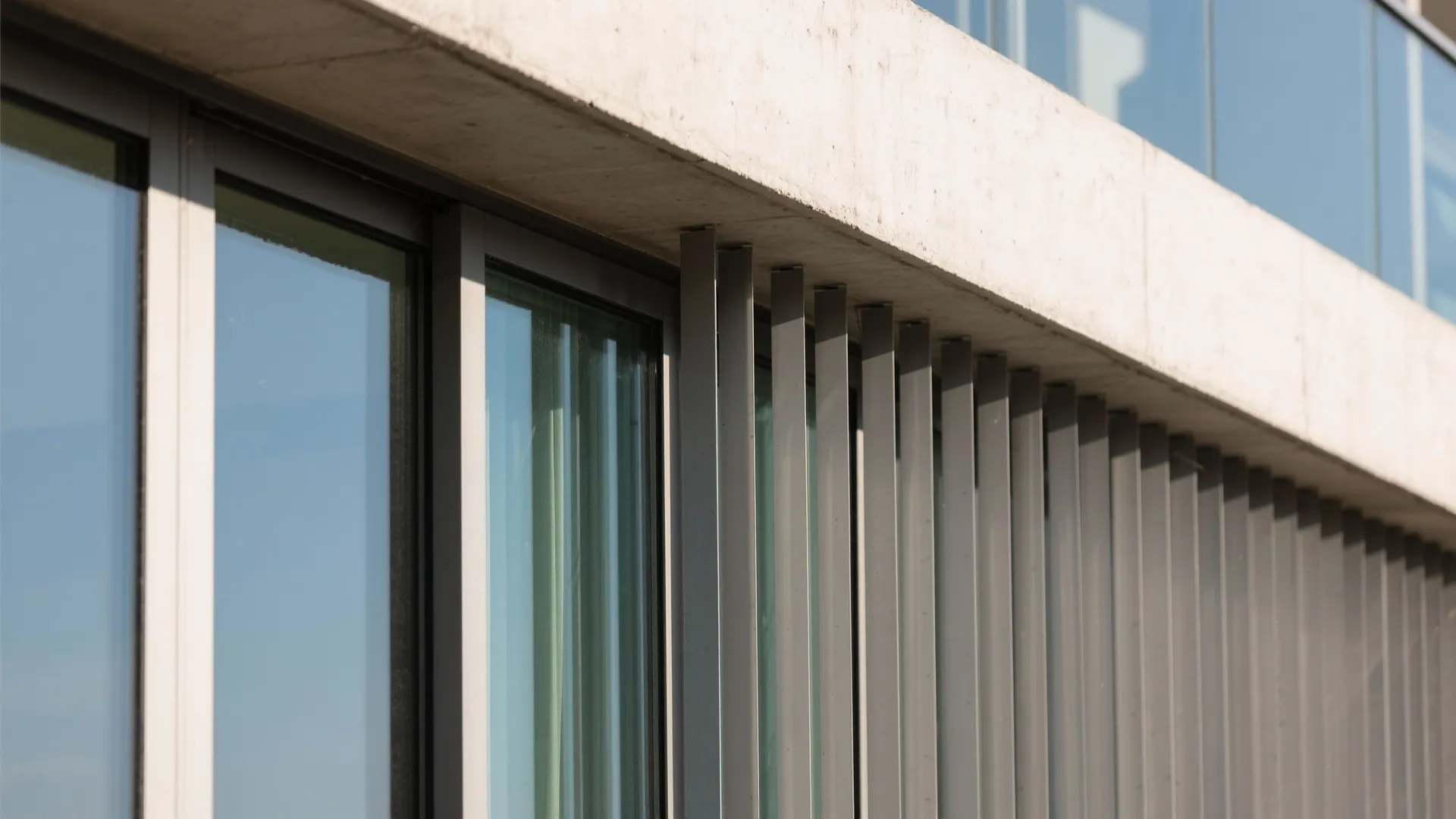 Close-up of balcony overhang and vertical fins shading sliding doors with low-SHGC glass.