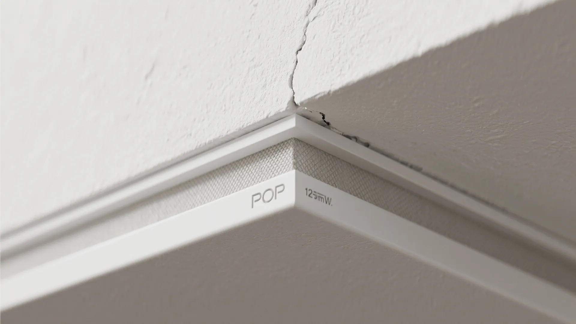 Close up of white ceiling light fixture corner detail showing clean lines and textured surface