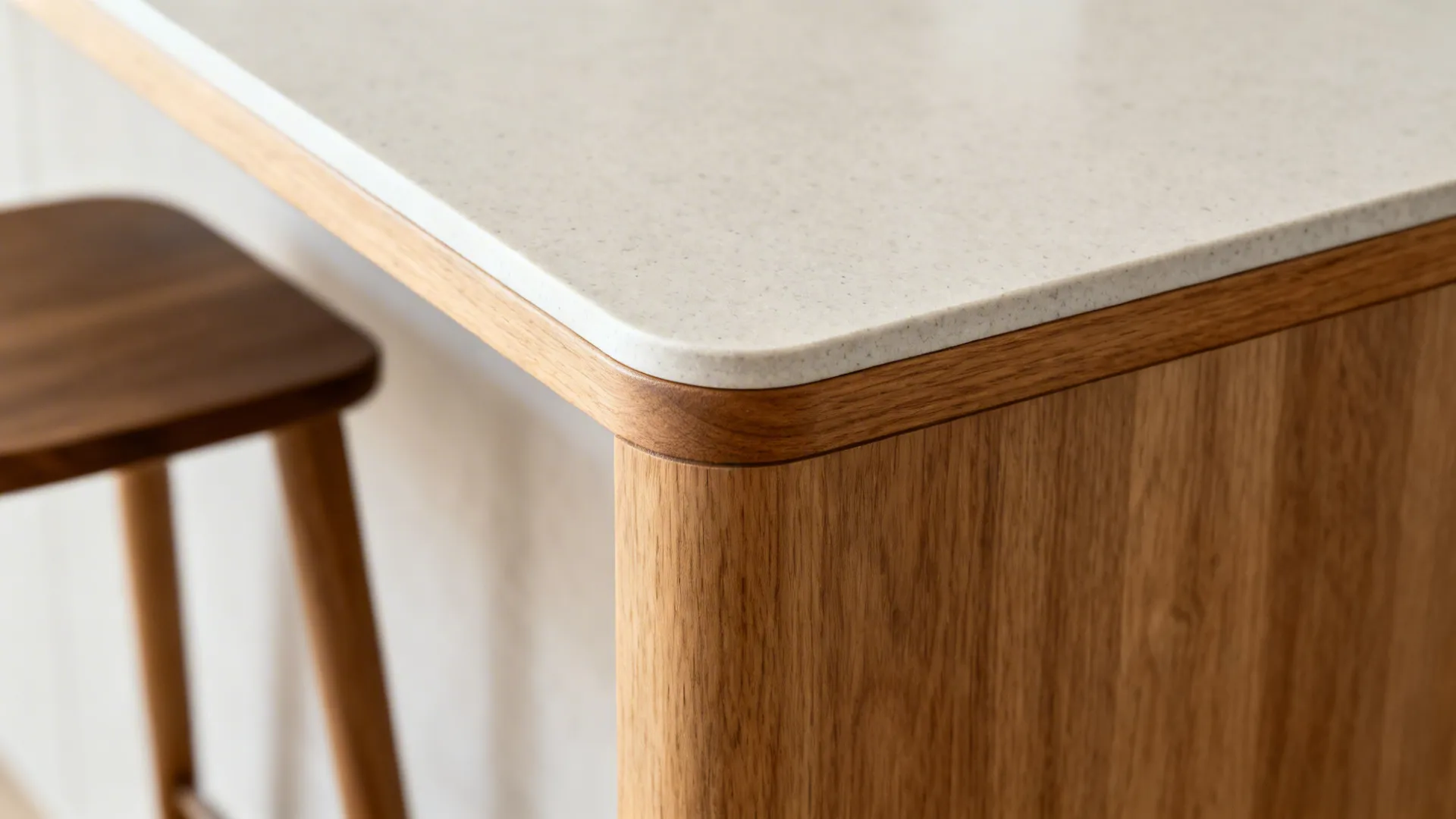 Macro of a rounded matte quartz peninsula corner with oak edge for a small kitchen bar.