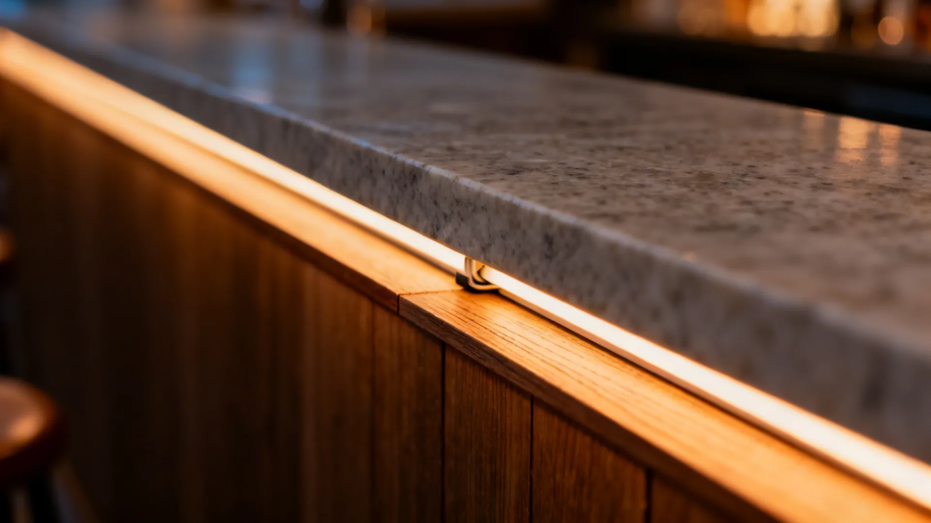 Close-up of a slender stone bar cap with warm undercounter LED lighting.