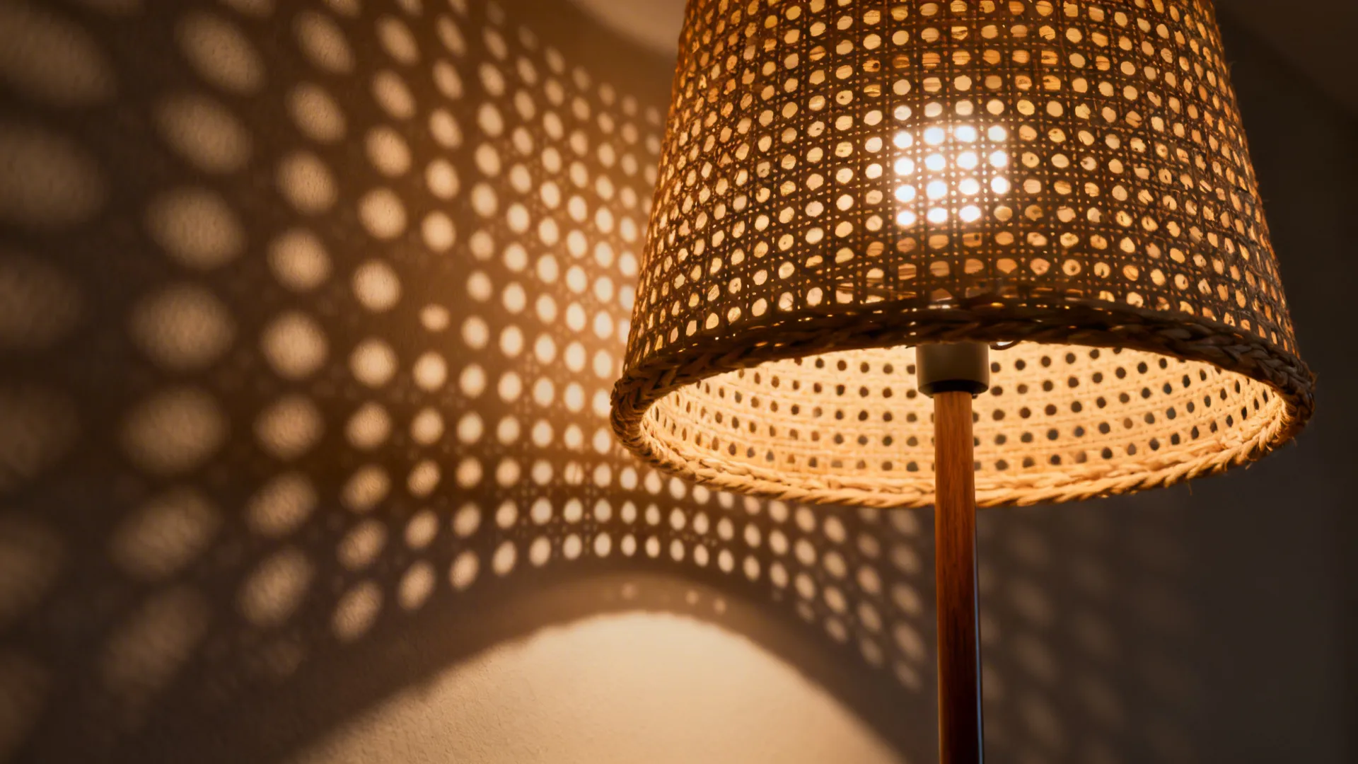 Close up of a woven light fixture casting patterned shadows on a plain white wall