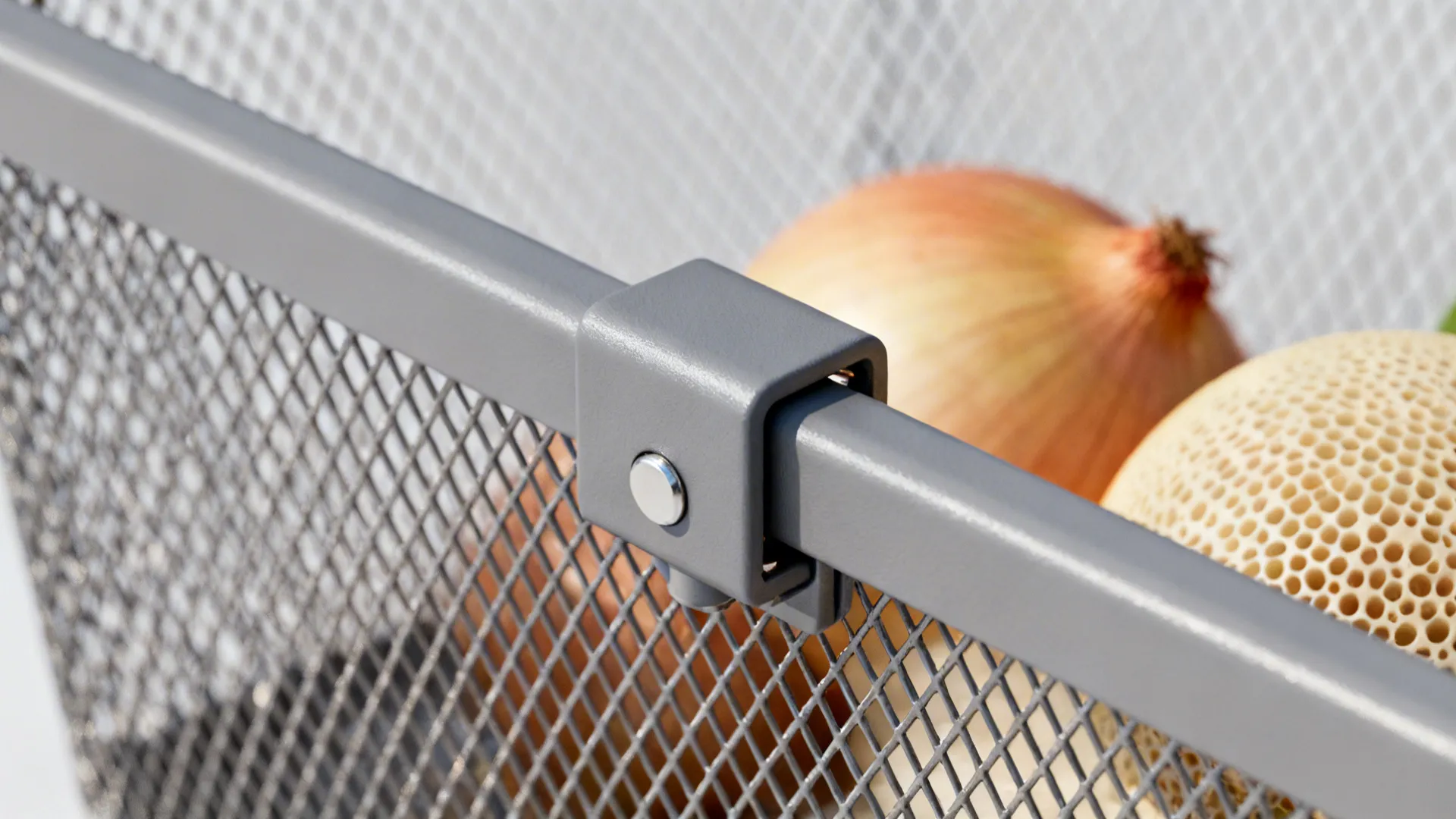 Close-up of a locking bracket attaching a mesh steel basket to a rail with an onion inside.