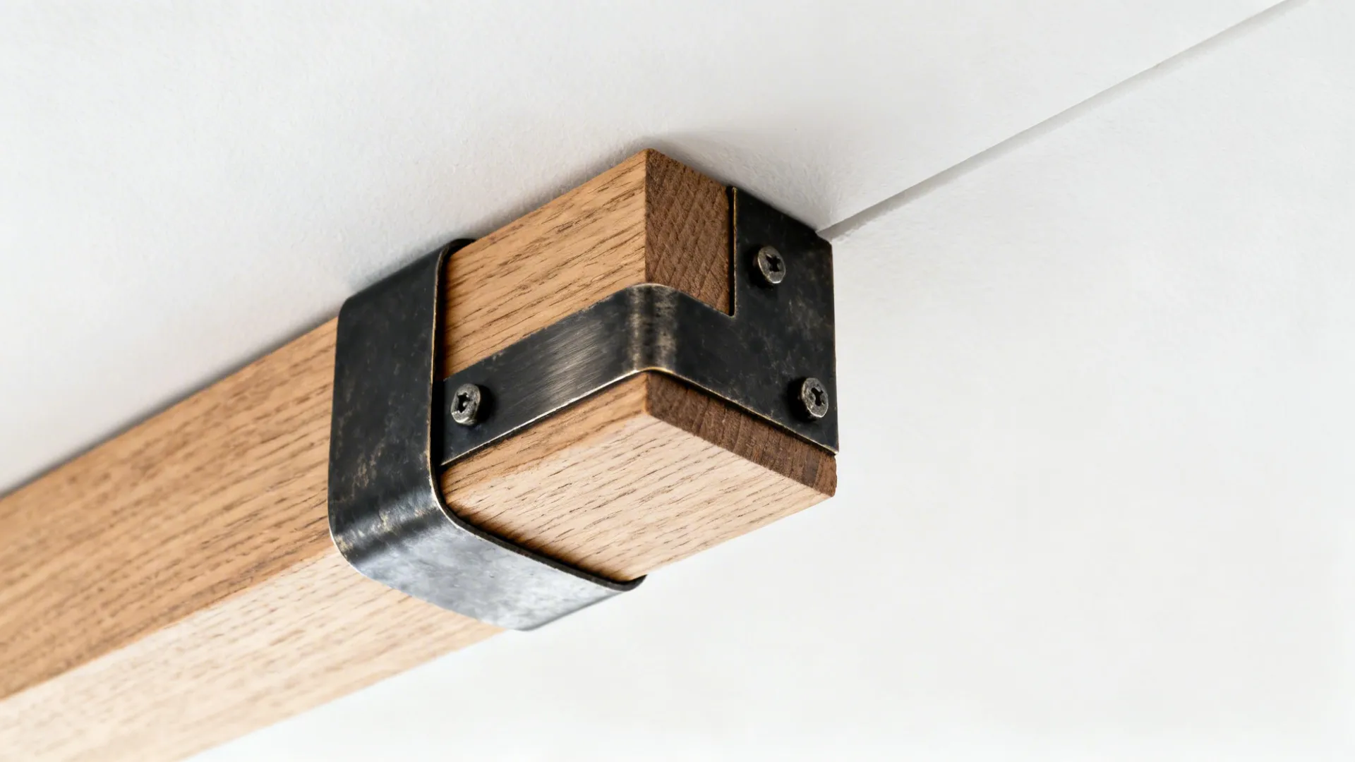 Close-up of a wood beam end wrapped with a blackened steel strap.