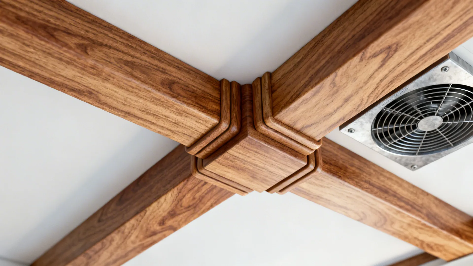 Brown wooden beams crossing on a white ceiling surface next to a small metal exhaust fan