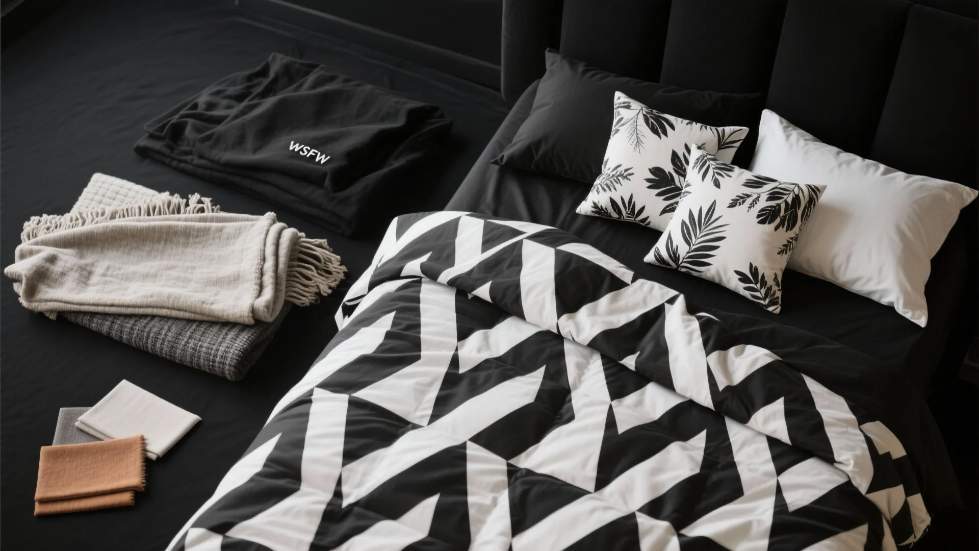 Top view of a bed with black and white geometric bedding plus leaf pattern throw pillows