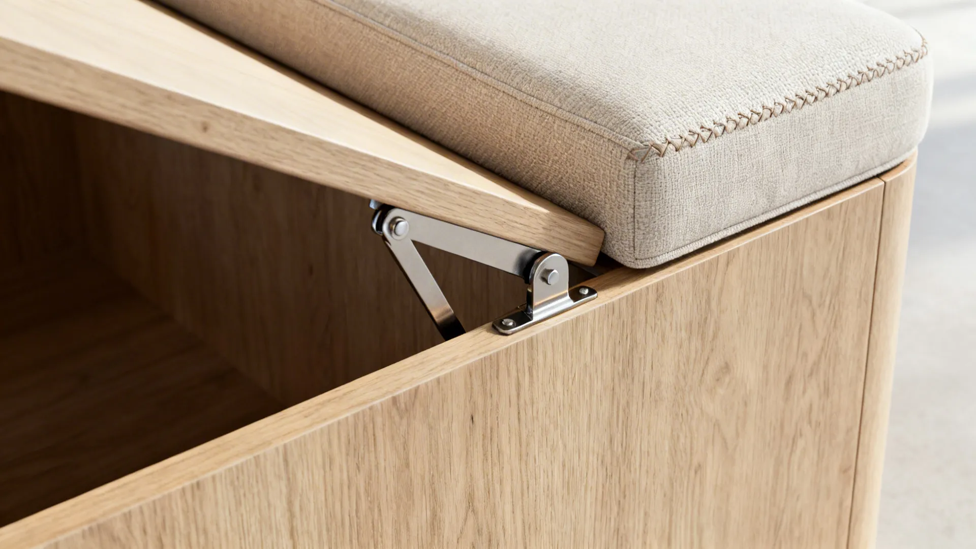 Close-up of lift-up bench hinge with soft-close hardware and cream cushion stitching.
