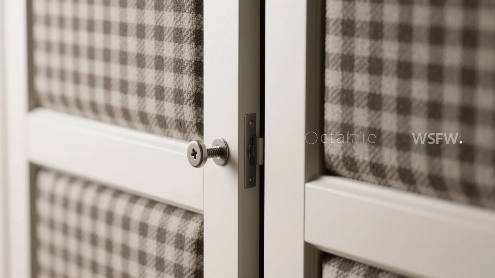 Close up of a metal screw connecting a white door frame with checkered fabric panel inserts