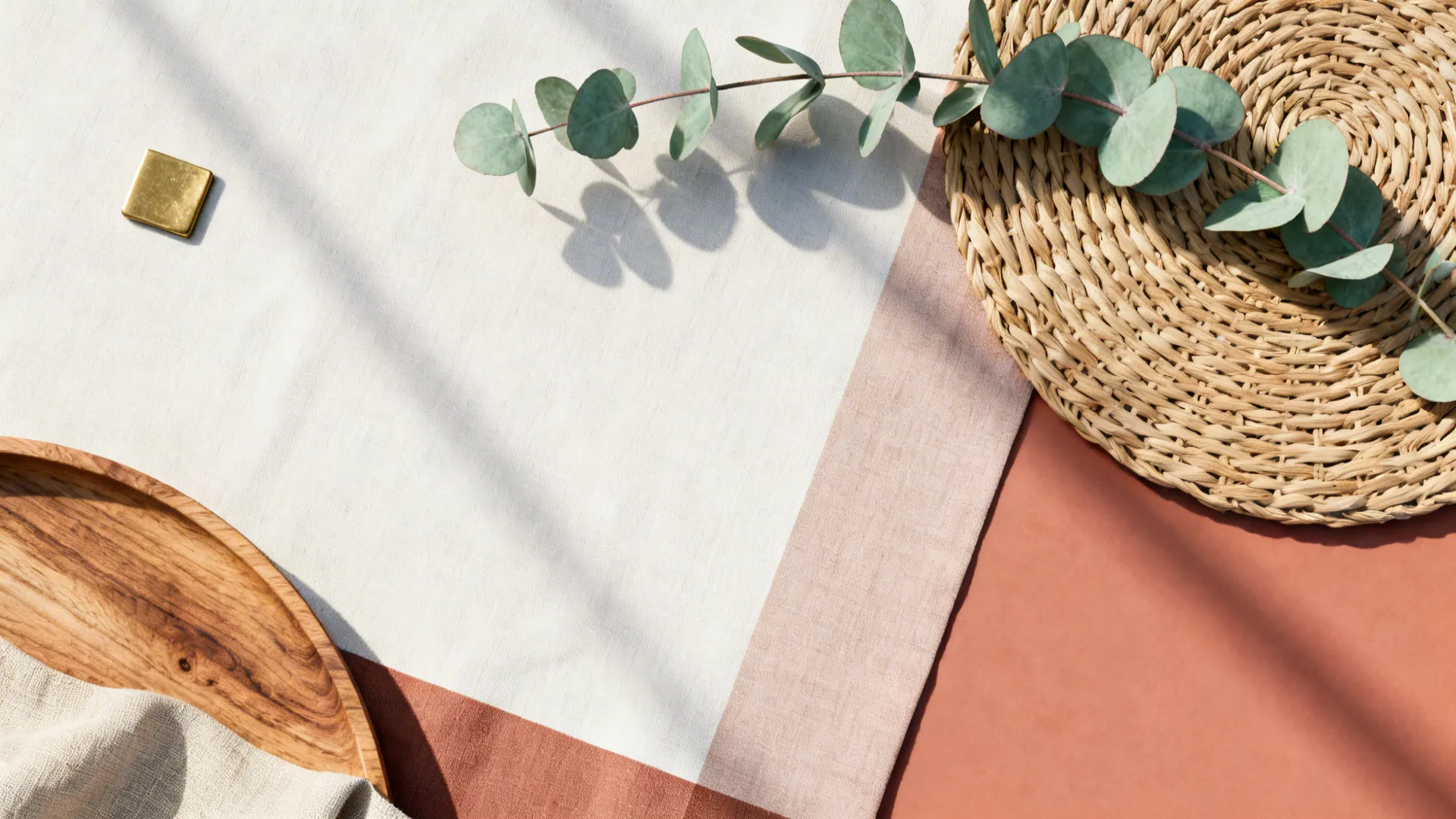 Flat lay with green leaves a straw mat wooden tray and fabric on a neutral background