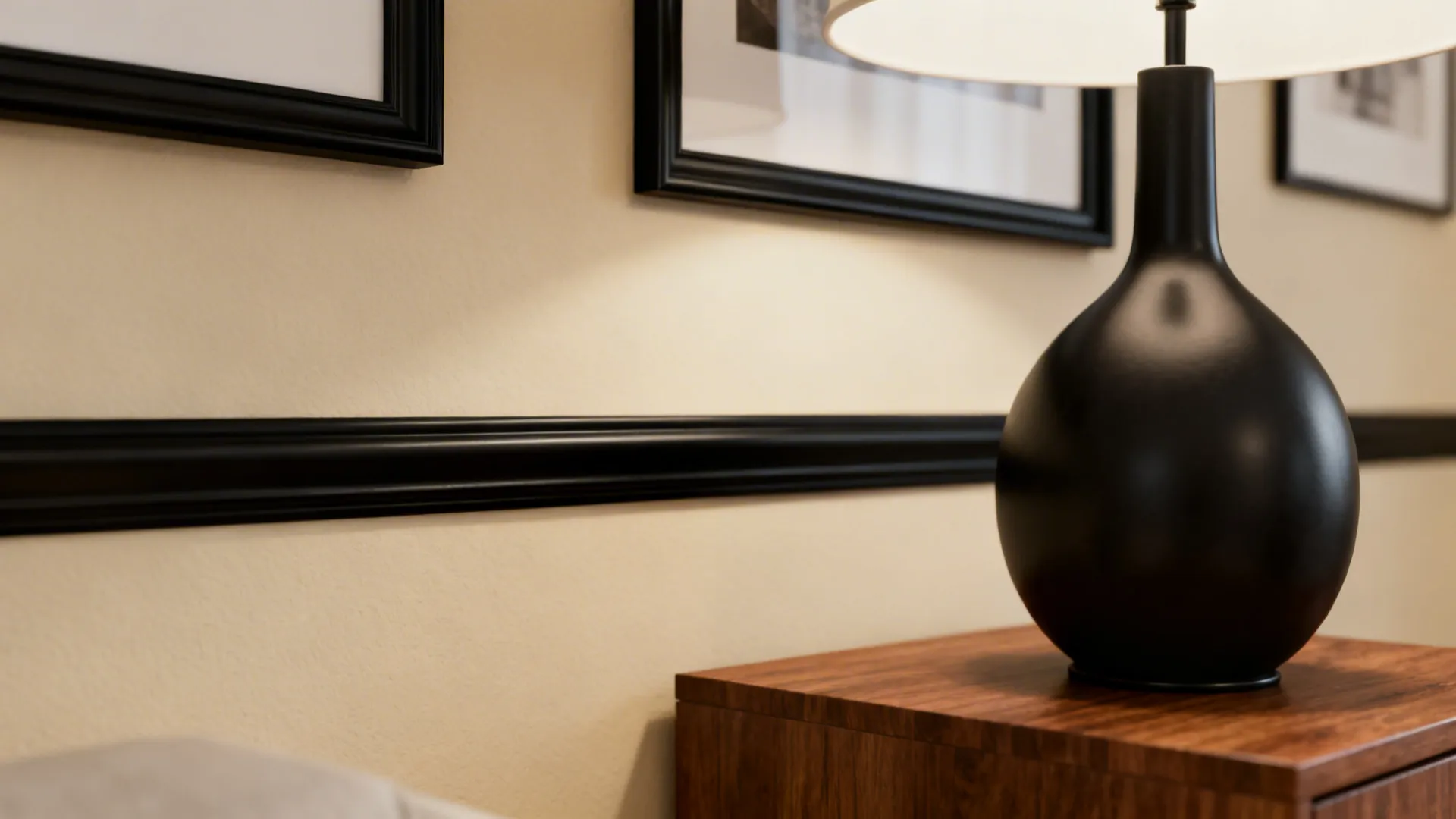 Curated black accents: frames, lamp base and bookshelf unifying a cream room