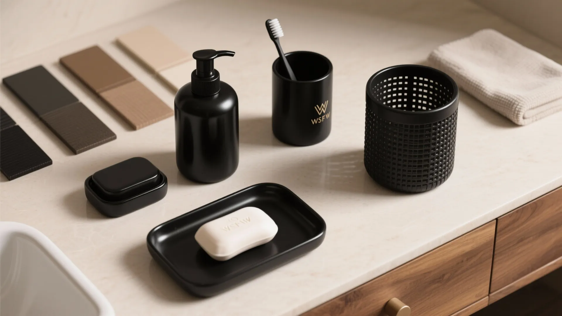 Top-down flatlay of coordinated matte and glossy black bathroom accessories next to wood swatches.