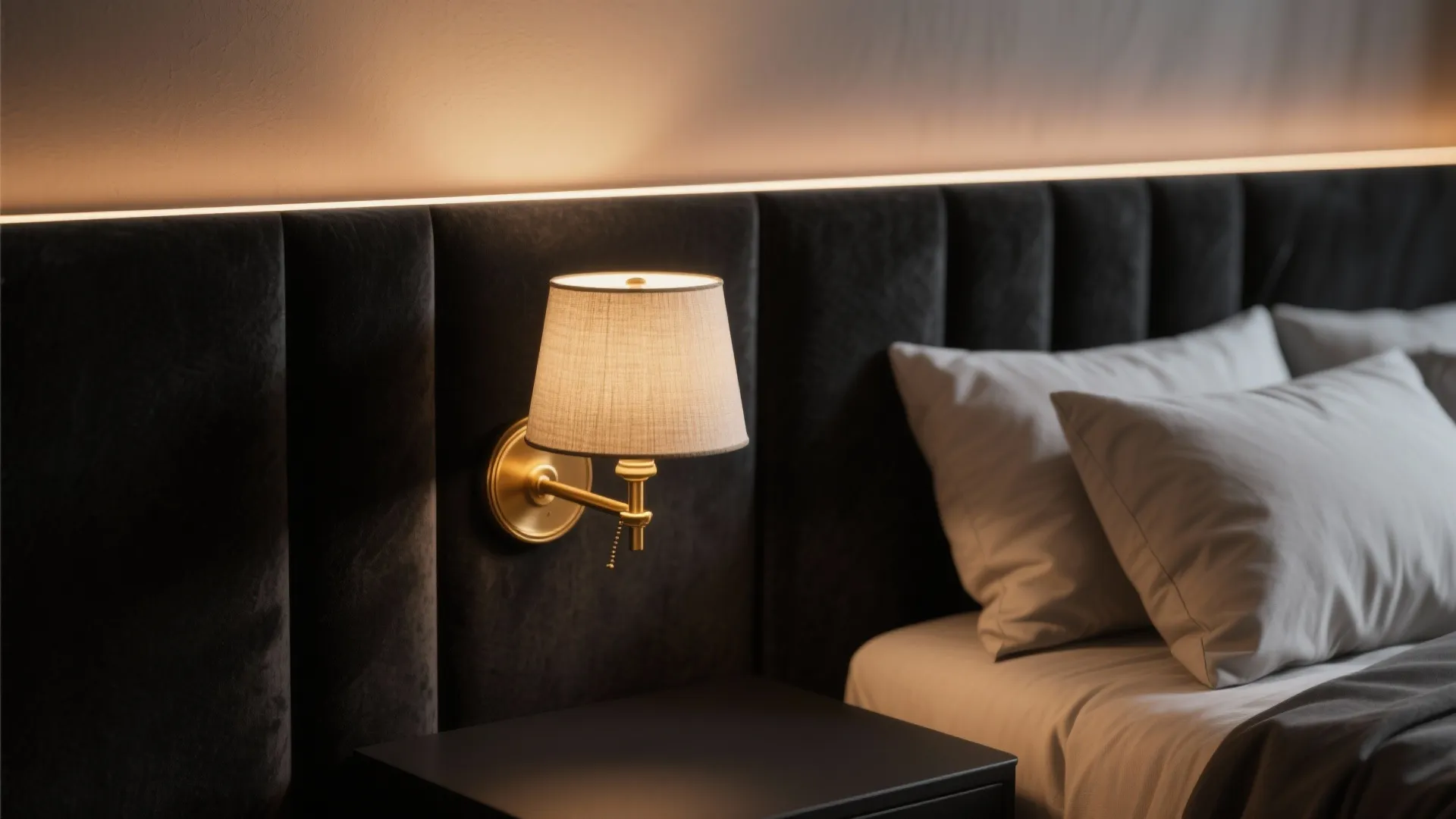 Modern wall light on a black wall panel beside a bed with white pillows and
