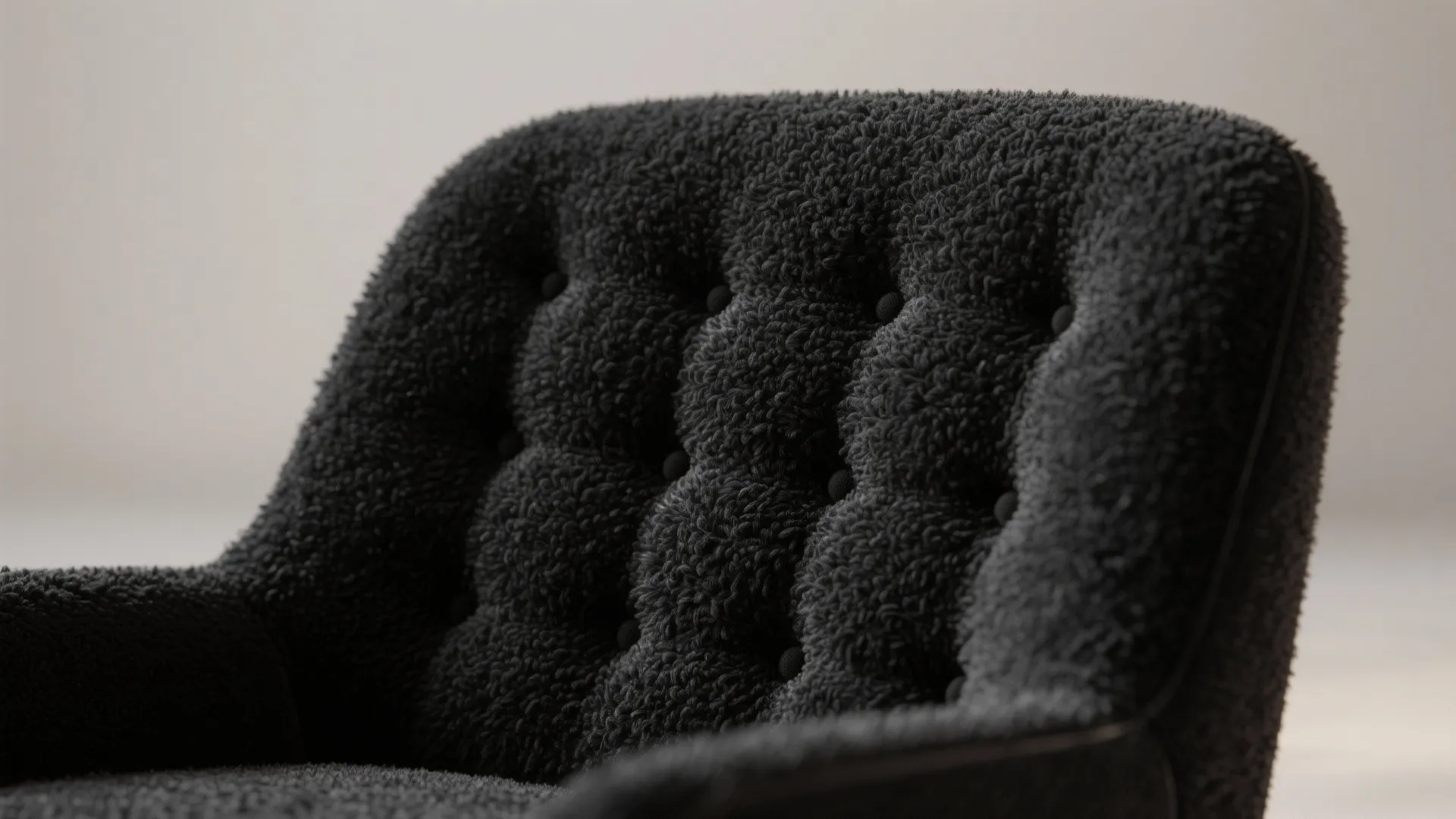 Macro view of black bouclé upholstery and tufting on an accent chair highlighting texture