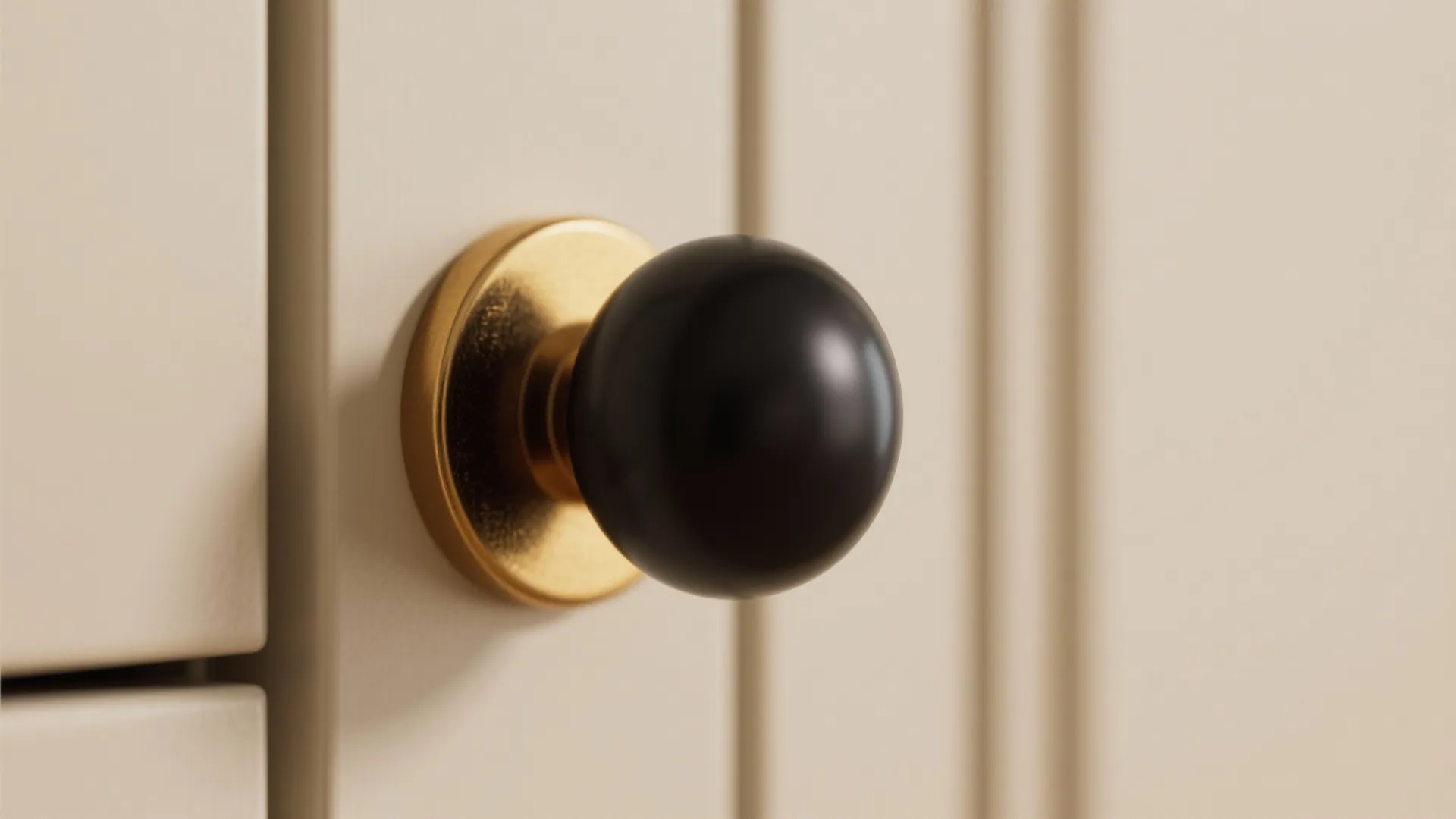 Close up of a round black handle with a gold base on a white cabinet