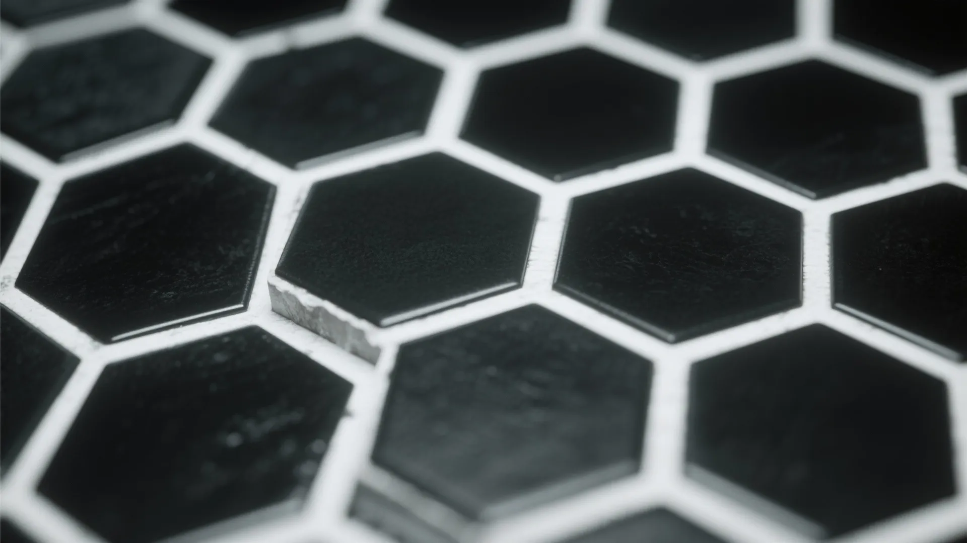 Macro view of matte black hex tiles outlined by white grout showing clear geometric pattern