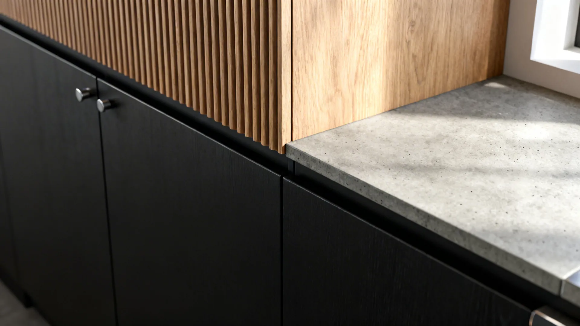 Macro of matte black cabinet meeting fluted oak panel with concrete-look counter edge.