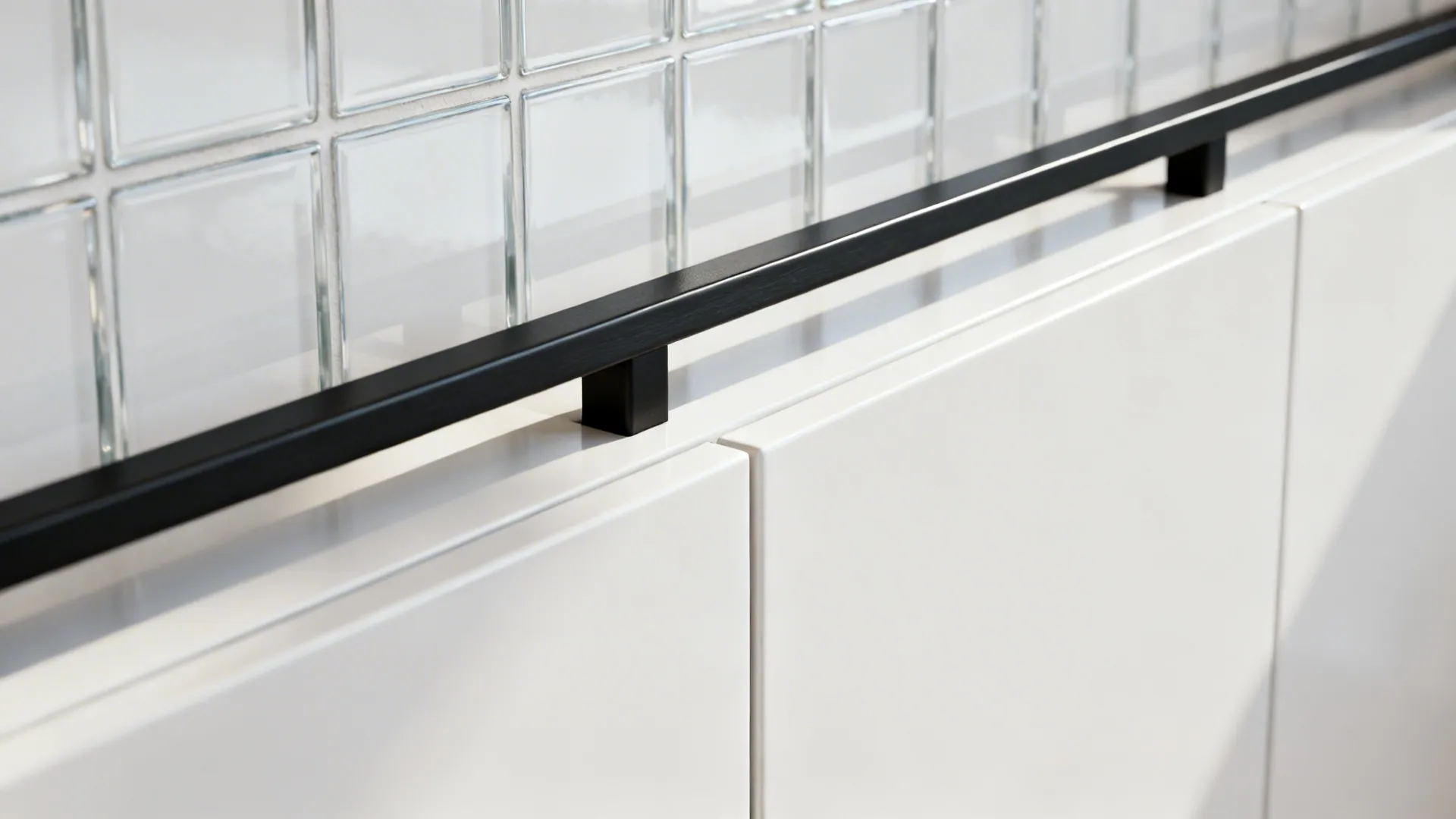 Macro of a thin black rail on a white splashback with satin cabinet edge.