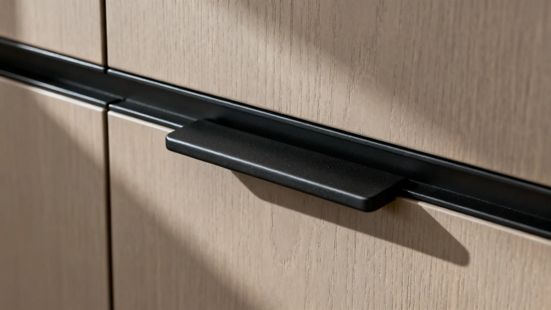Macro of matte black rail and handle on greige cabinet showing refined texture and finish.